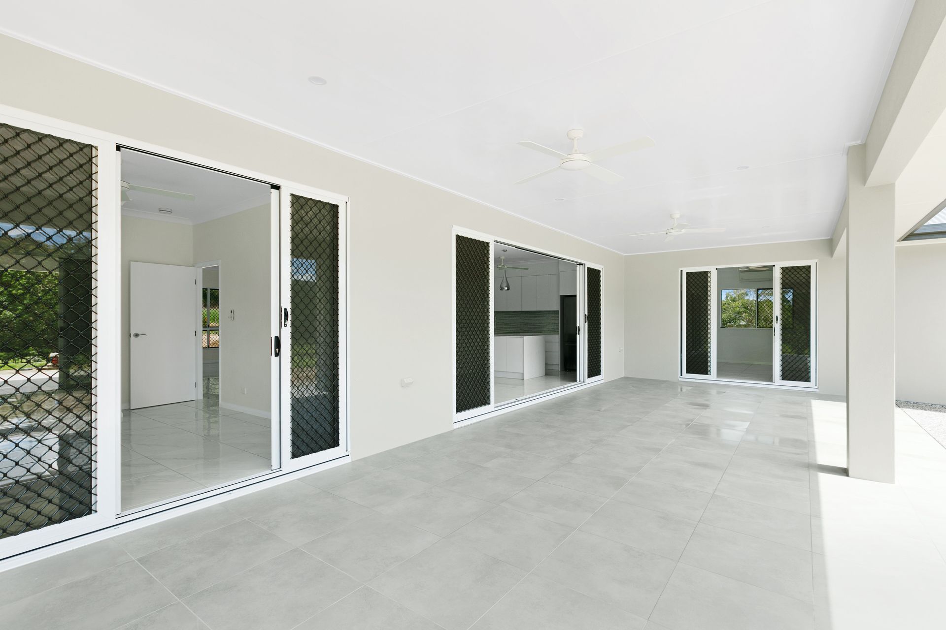 An Outdoor Patio With Light Gray Tiled Flooring and White Walls — Ashlee Jones Homes in Gordonvale, QLD