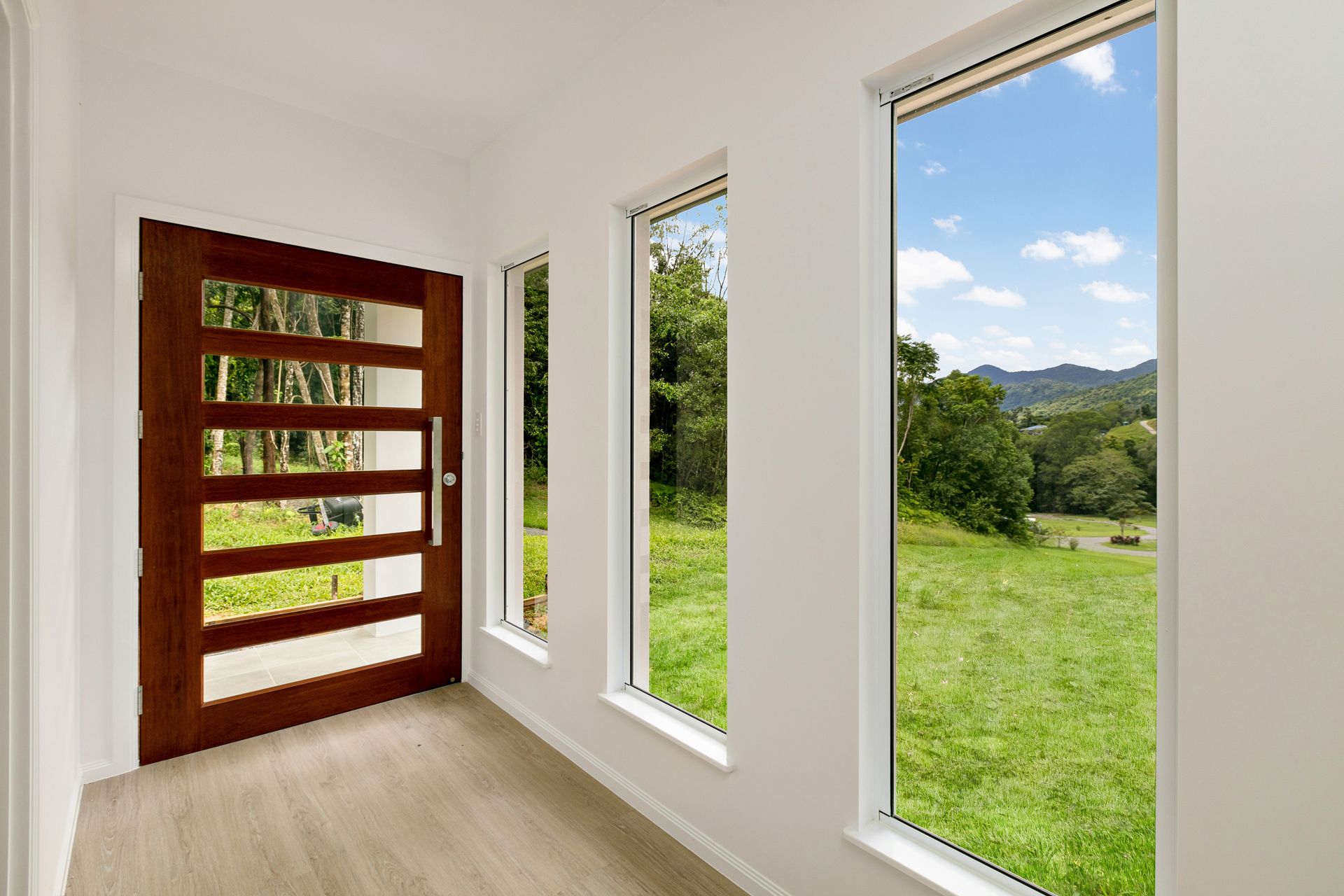 A Bright Entryway With a Modern Wood Paneled Door — Ashlee Jones Homes in Gordonvale, QLD