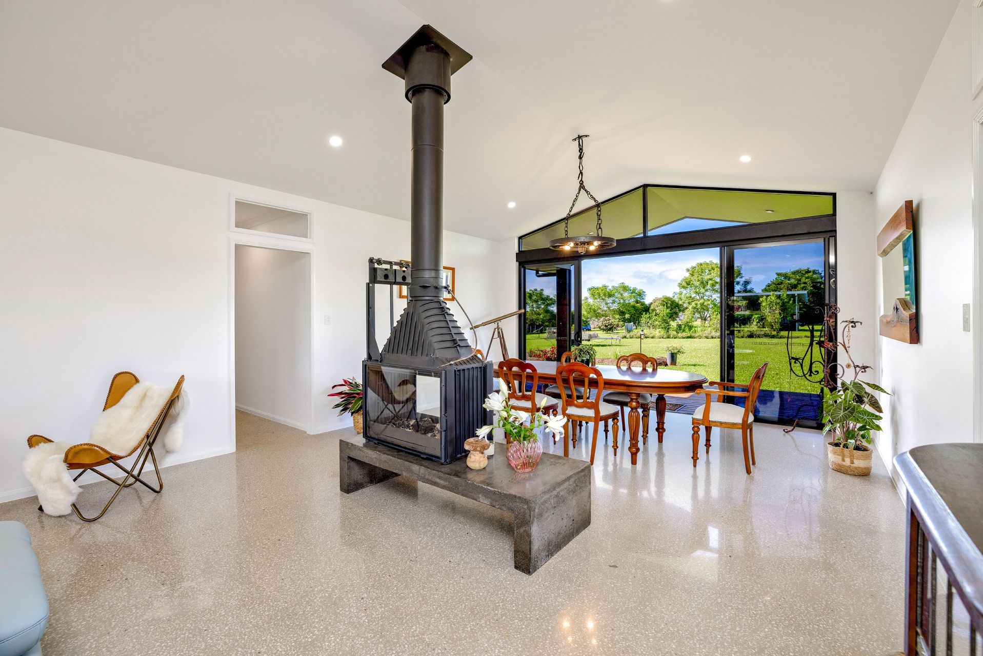 A Bright Open-plan Room With a Central Black Metal Fireplace — Ashlee Jones Homes in Gordonvale, QLD