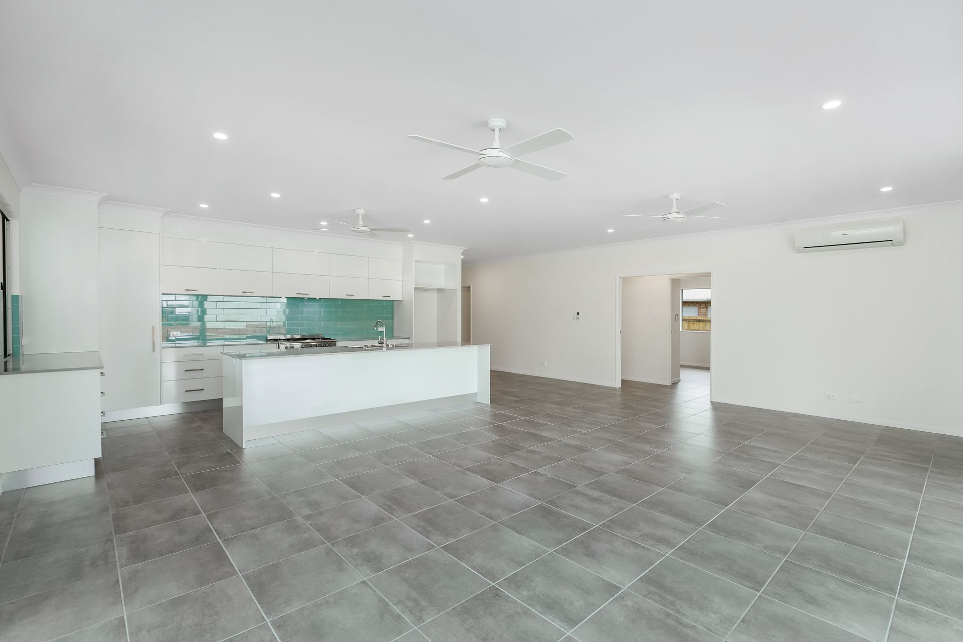 A Modern, Open-plan Kitchen and Living Space With White Cabinetry — Ashlee Jones Homes in Gordonvale, QLD