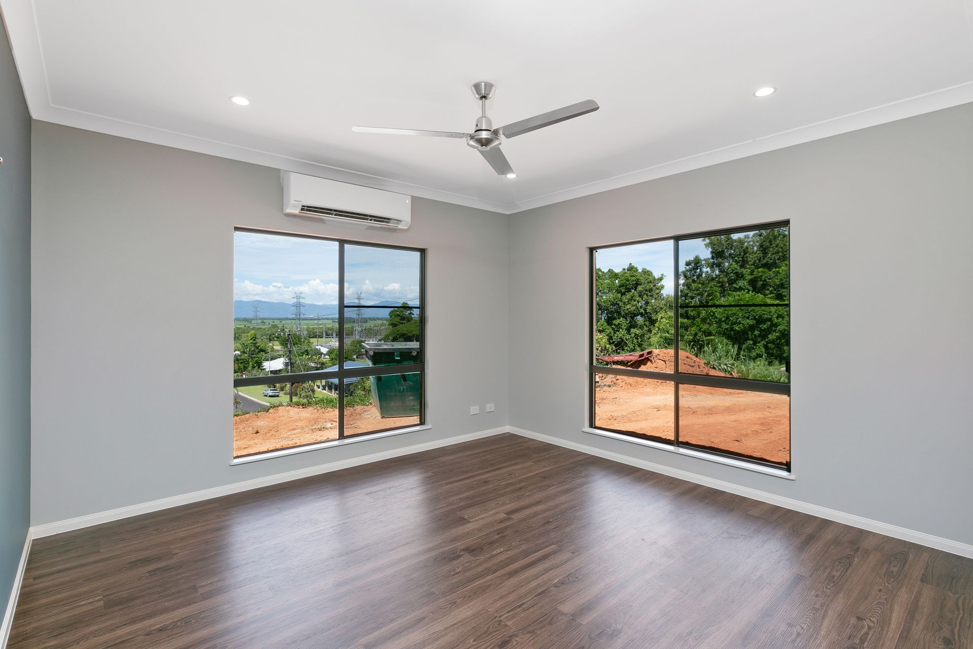 A Bright, Empty Bedroom With Grey Walls, Dark Wood Floors — Ashlee Jones Homes in Gordonvale, QLD