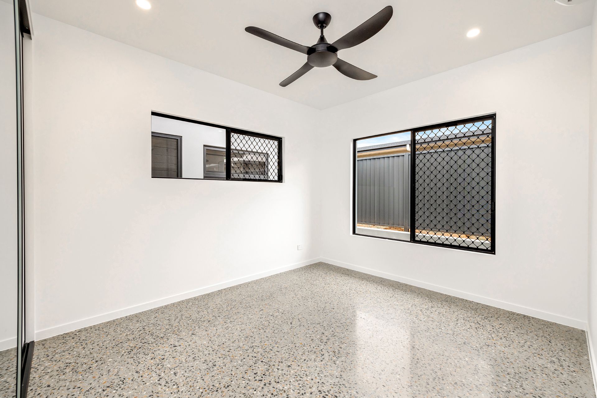 A Bright, Modern Empty Room With White Walls, a Black Ceiling Fan — Ashlee Jones Homes in Gordonvale, QLD