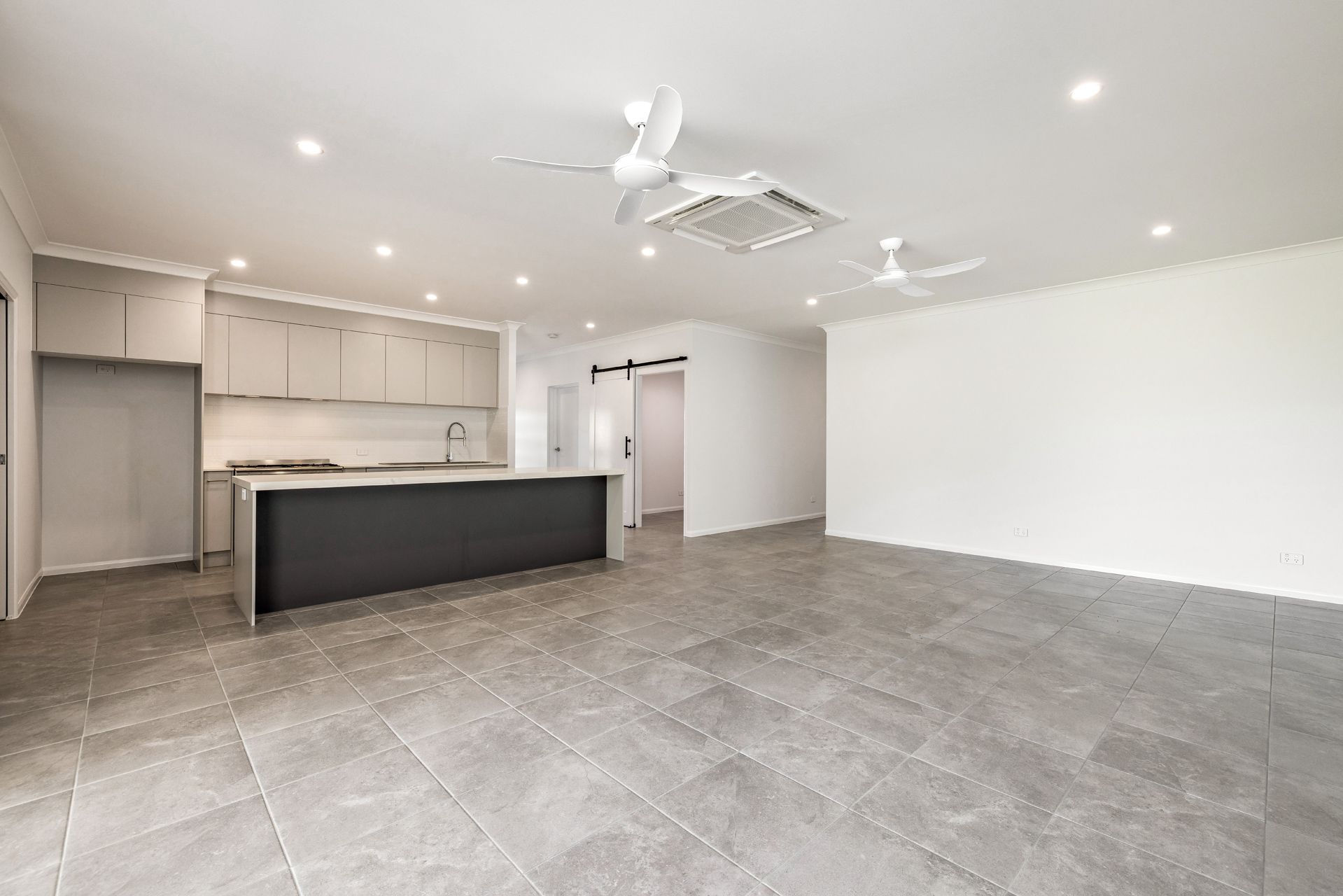 Modern Open-plan Kitchen and Living Space With Grey Tiled Flooring — Ashlee Jones Homes in Gordonvale, QLD