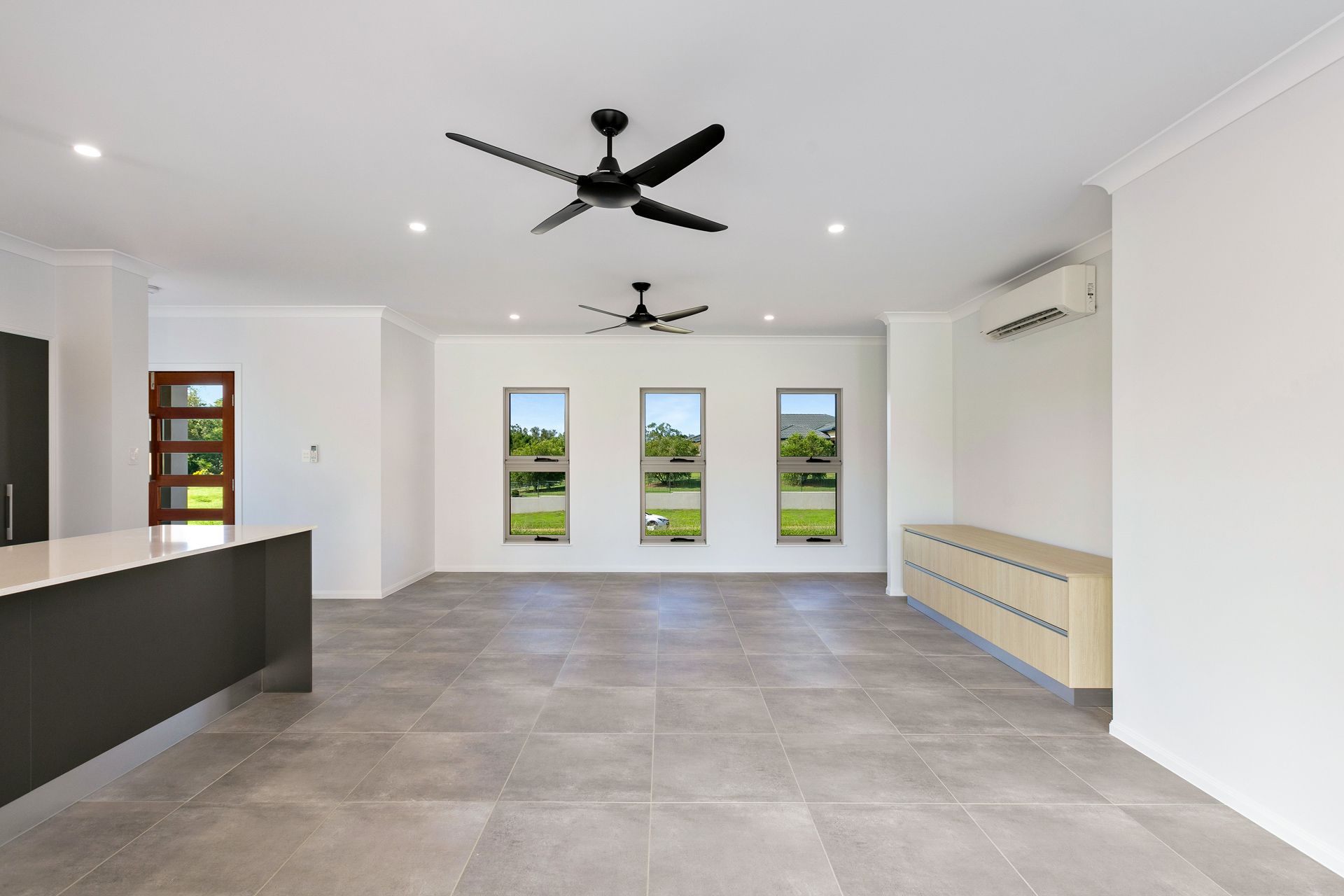 An Open-plan Room With Grey Tile Floors, White Walls — Ashlee Jones Homes in Gordonvale, QLD