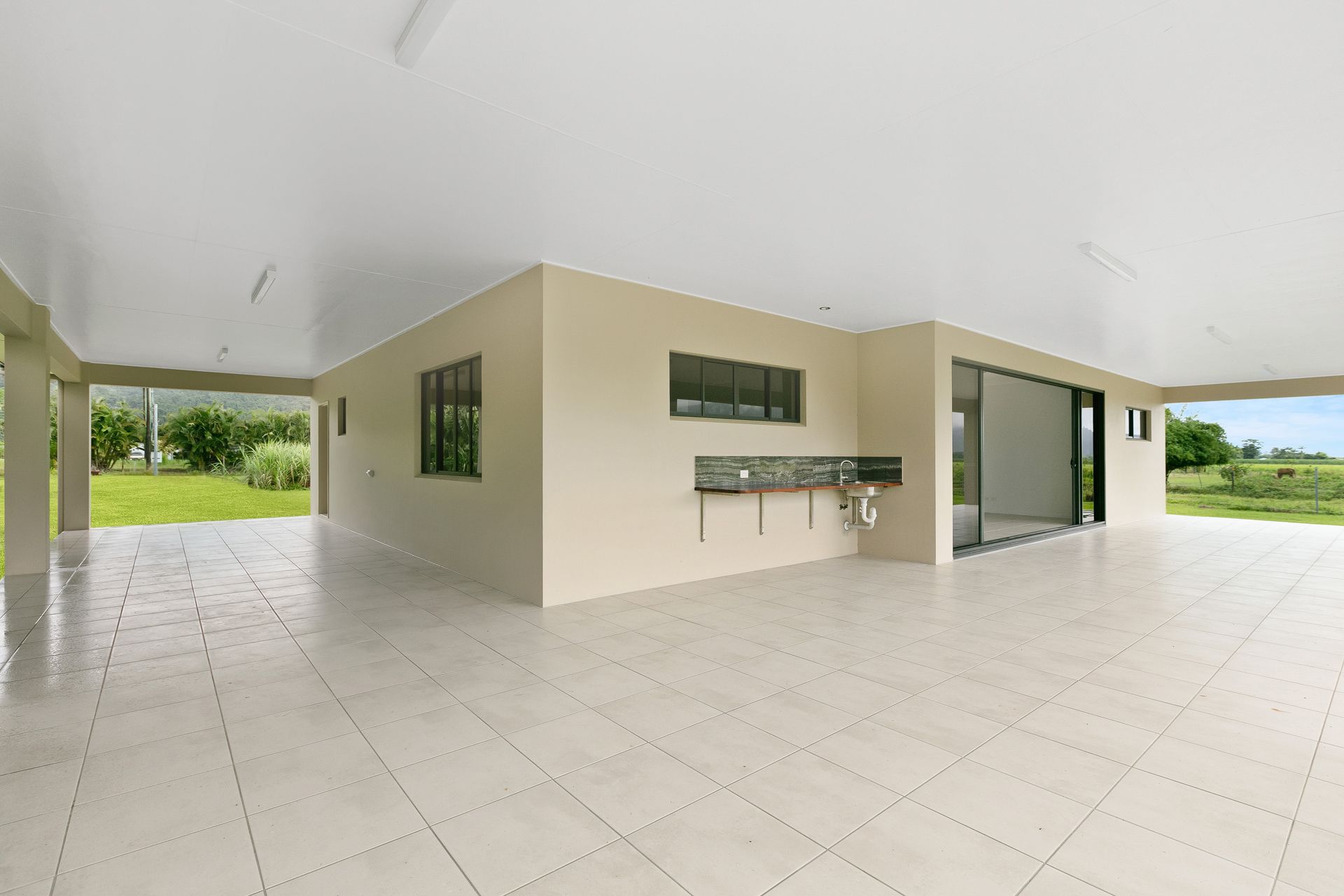A Covered Outdoor Patio Featuring Light-colored Tiled Floors — Ashlee Jones Homes in Gordonvale, QLD