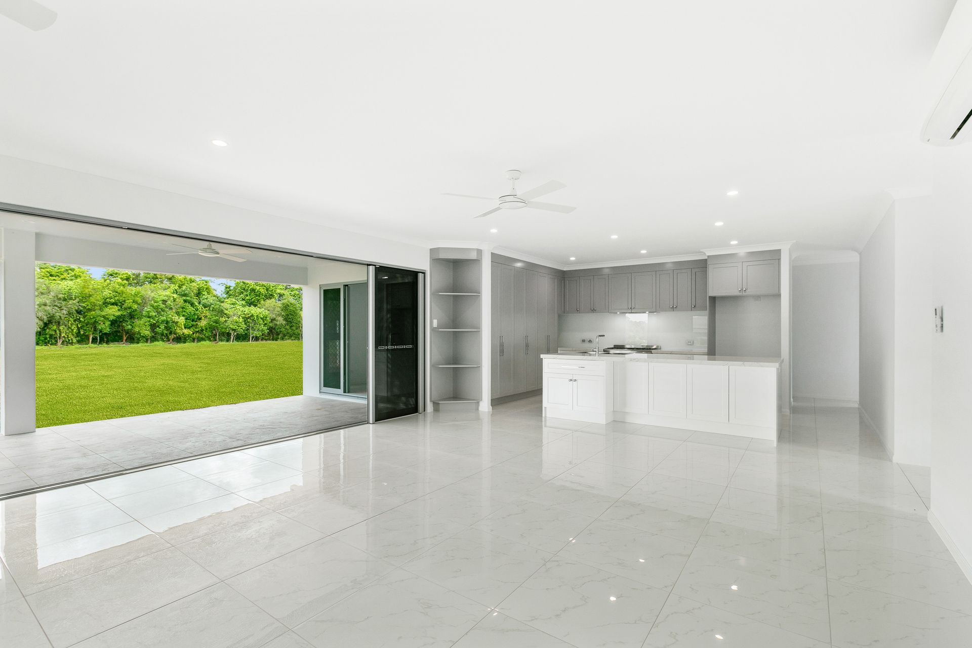 A Bright, Open-plan Kitchen and Living Area With White Tiled Floors — Ashlee Jones Homes in Gordonvale, QLD
