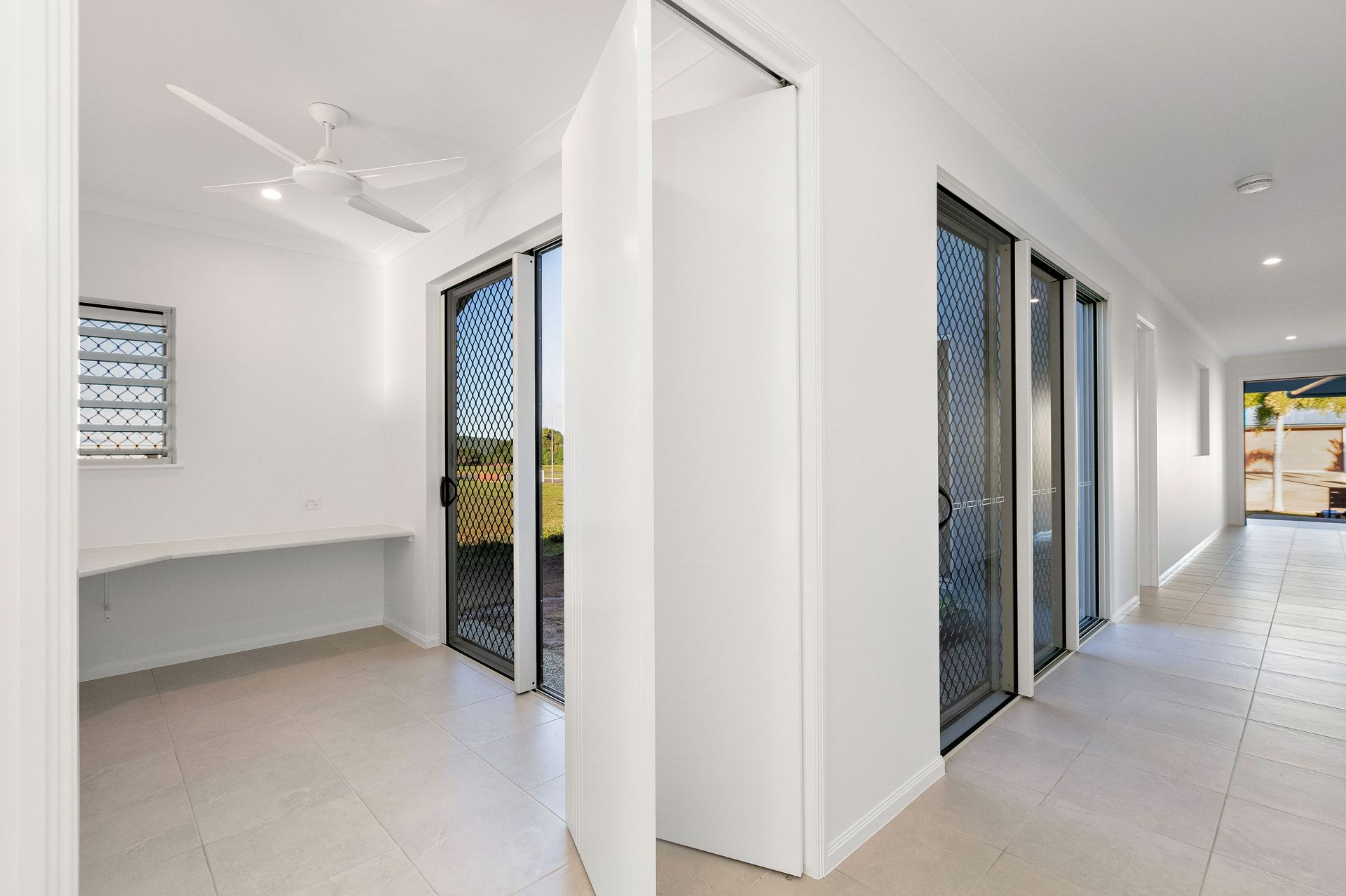 A Modern, White-walled Hallway Leads to a Room With a Built-in Desk — Ashlee Jones Homes in Gordonvale, QLD