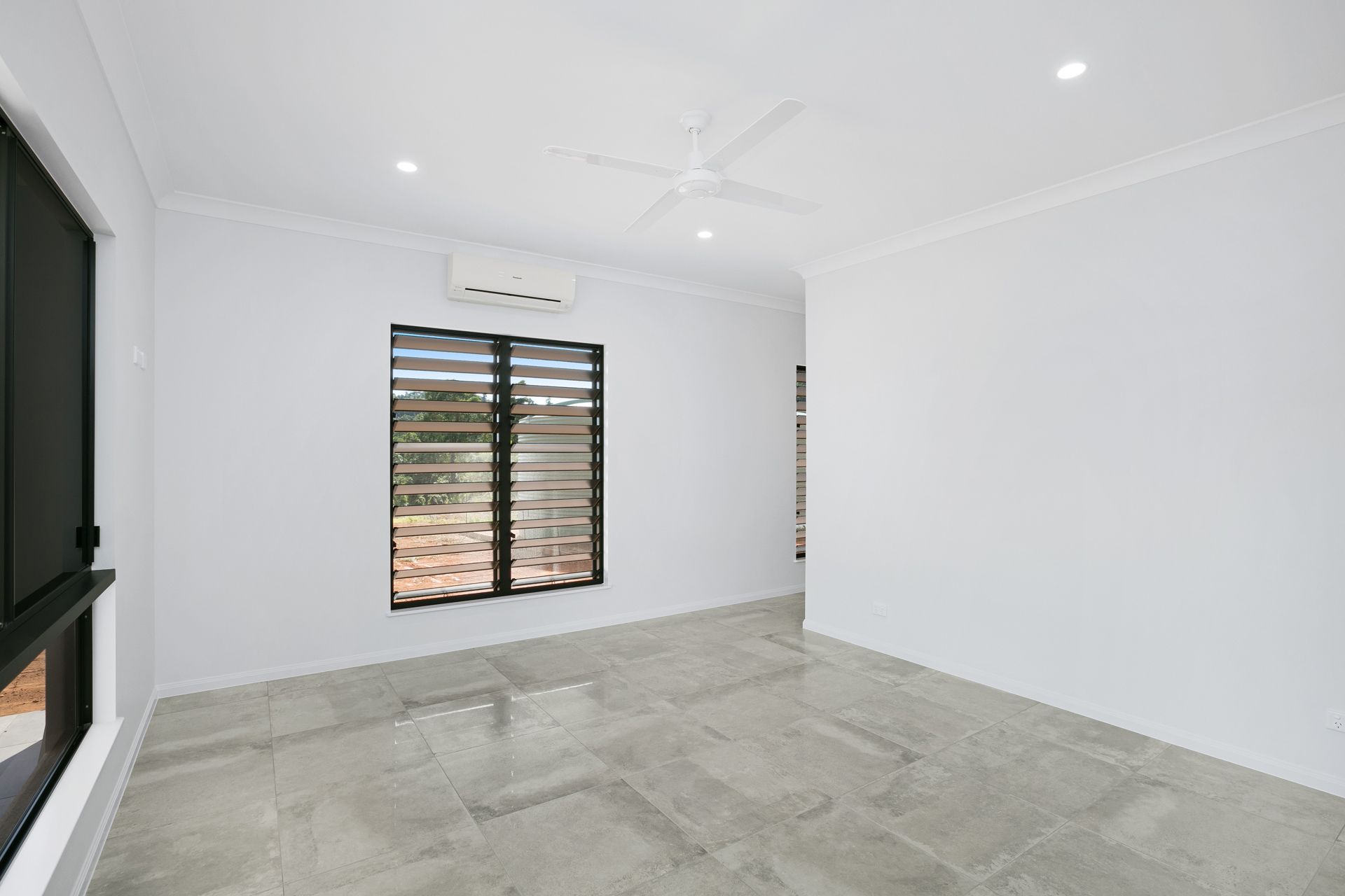 An Empty, Minimalist Room With White Walls, Grey Tiled Flooring — Ashlee Jones Homes in Gordonvale, QLD