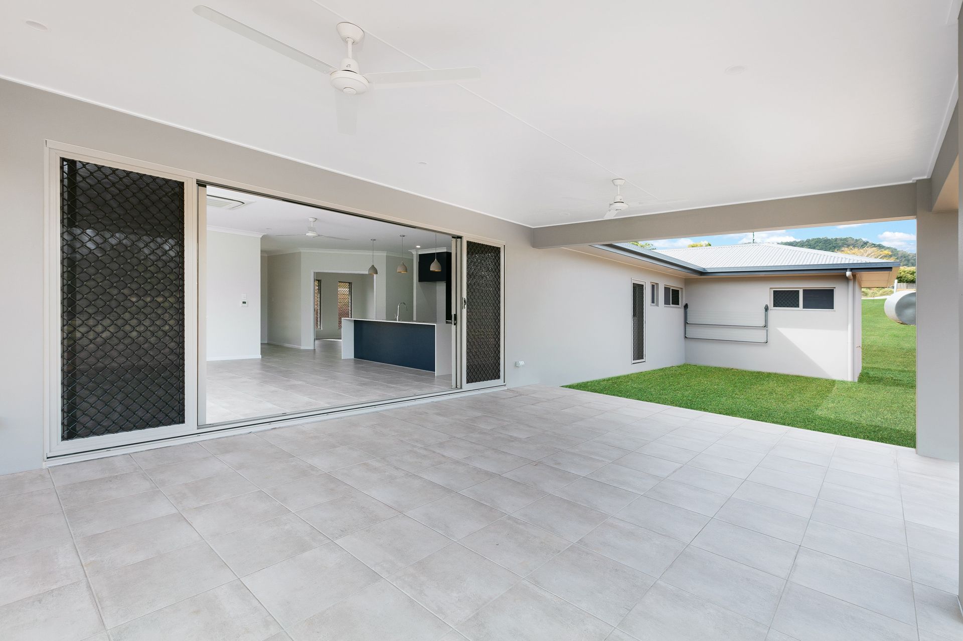 A Covered Outdoor Patio With Light Grey Tiled Floors — Ashlee Jones Homes in Gordonvale, QLD