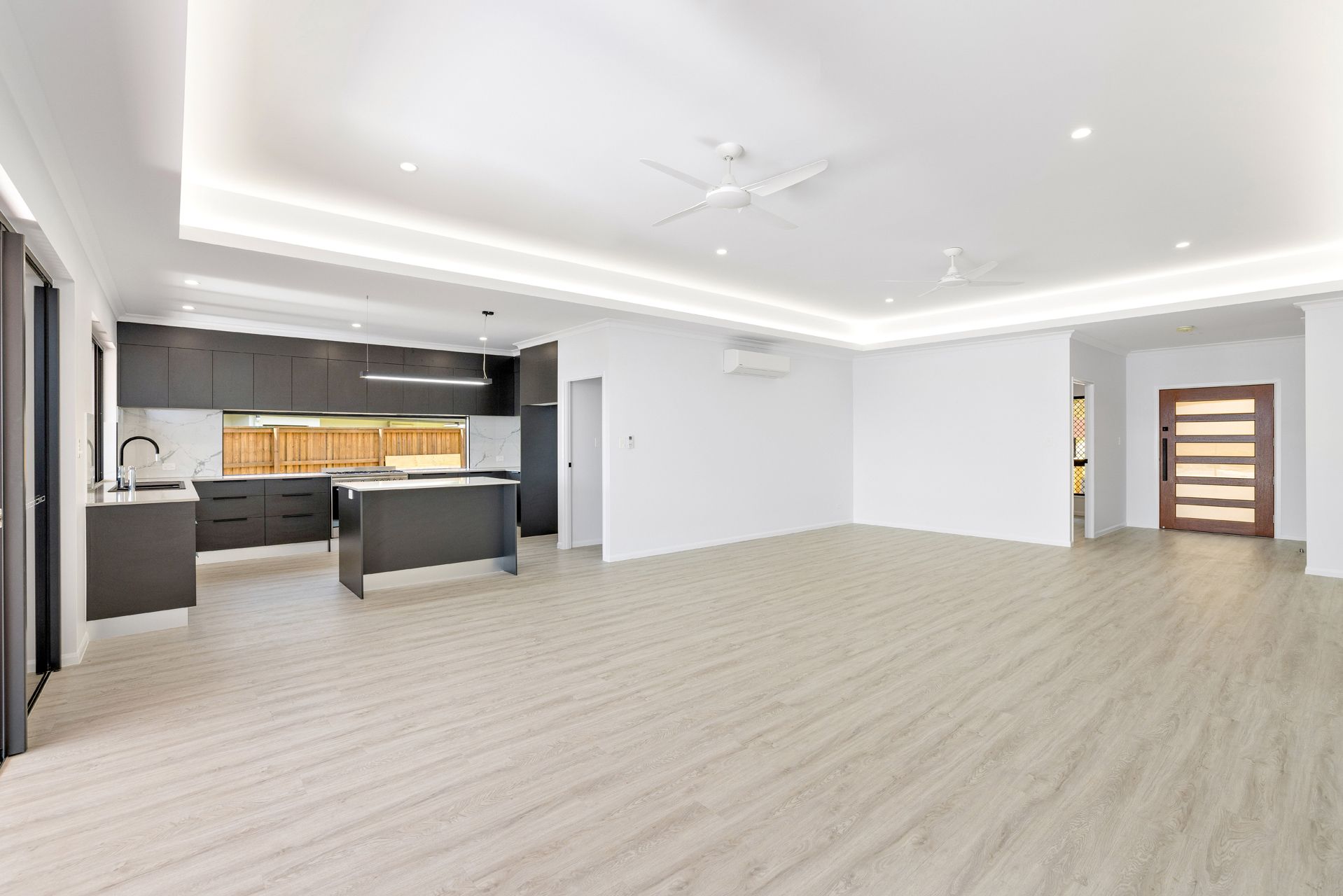 A Modern, Open-plan Living Area Featuring a Dark-toned Kitchen — Ashlee Jones Homes in Gordonvale, QLD