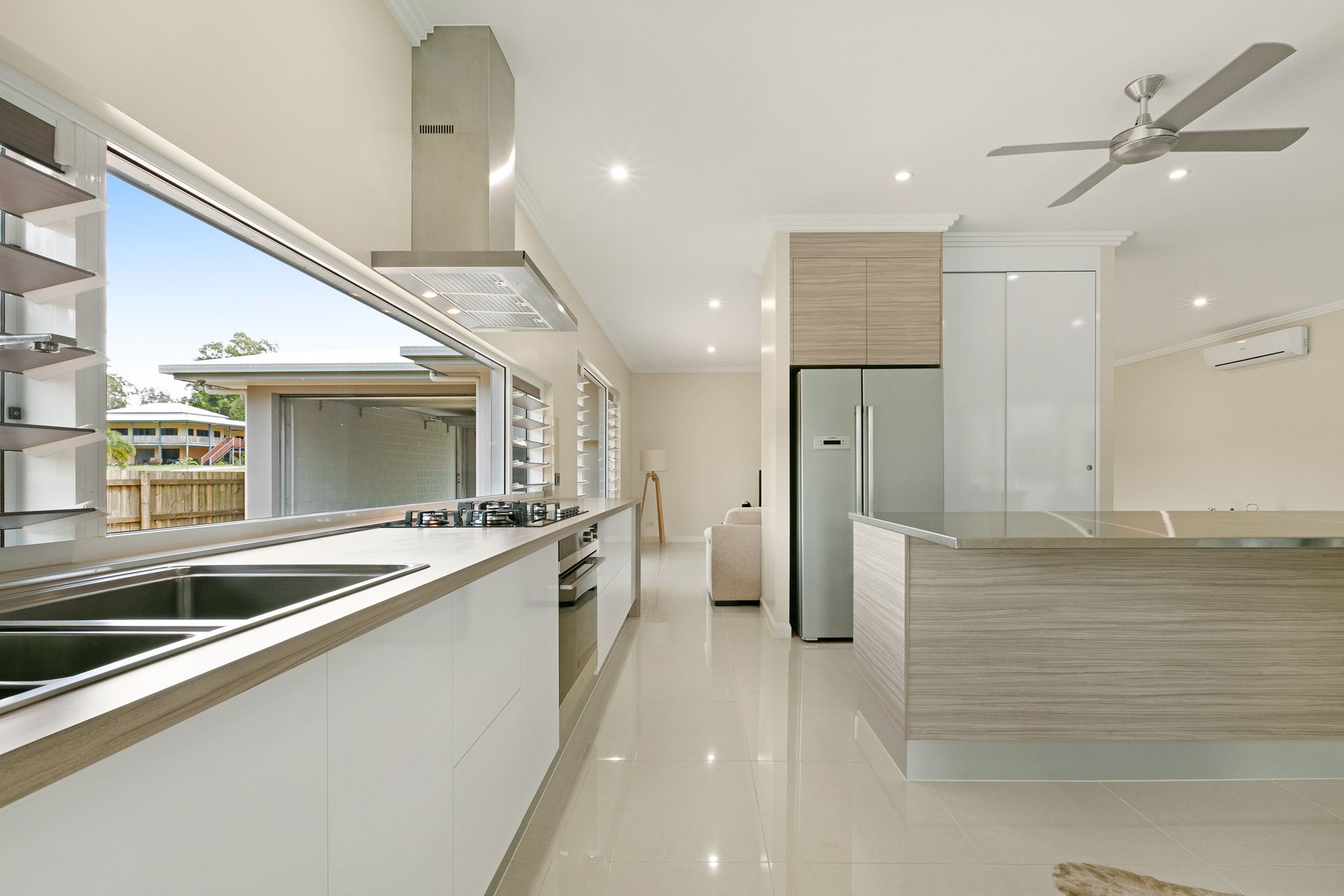 A Modern Kitchen With White Cabinetry, a Wood-grain Island — Ashlee Jones Homes in Gordonvale, QLD