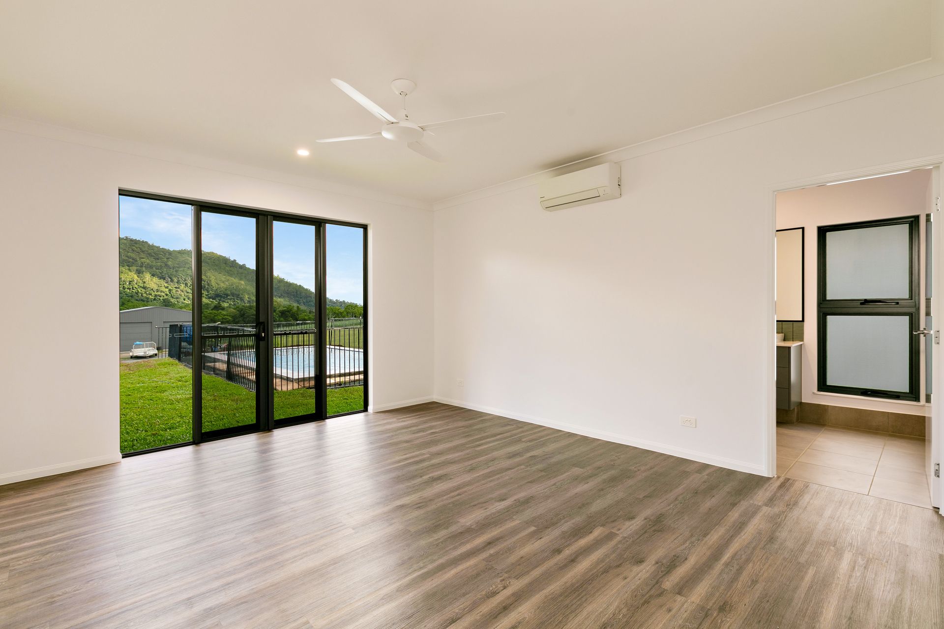 An Empty Room With Light Wood Flooring, White Walls, a Ceiling Fan — Ashlee Jones Homes in Gordonvale, QLD