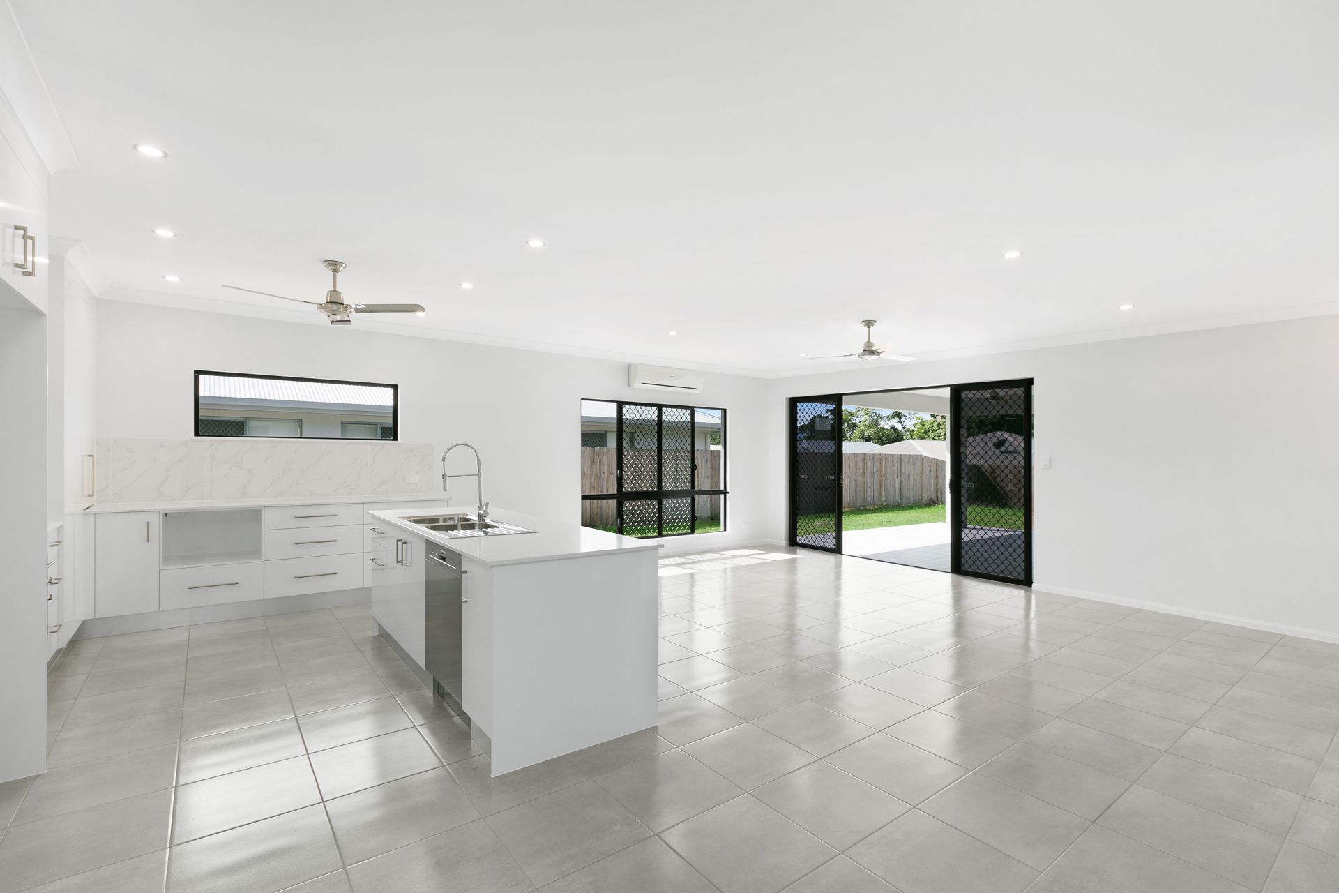 An Open-plan Kitchen and Living Area With White Walls — Ashlee Jones Homes in Gordonvale, QLD