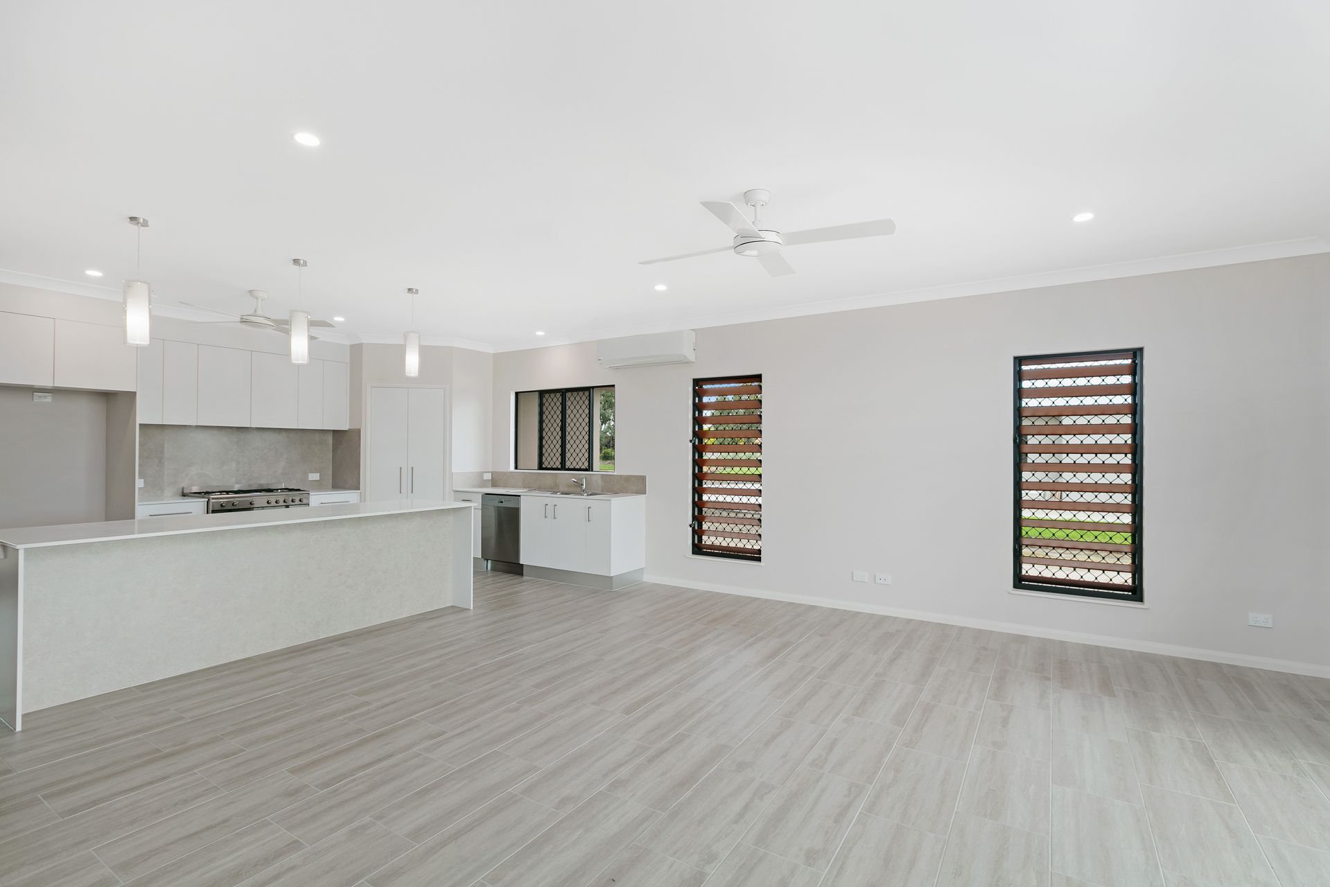 A Bright, Open-plan Kitchen and Living Area With White Walls — Ashlee Jones Homes in Gordonvale, QLD