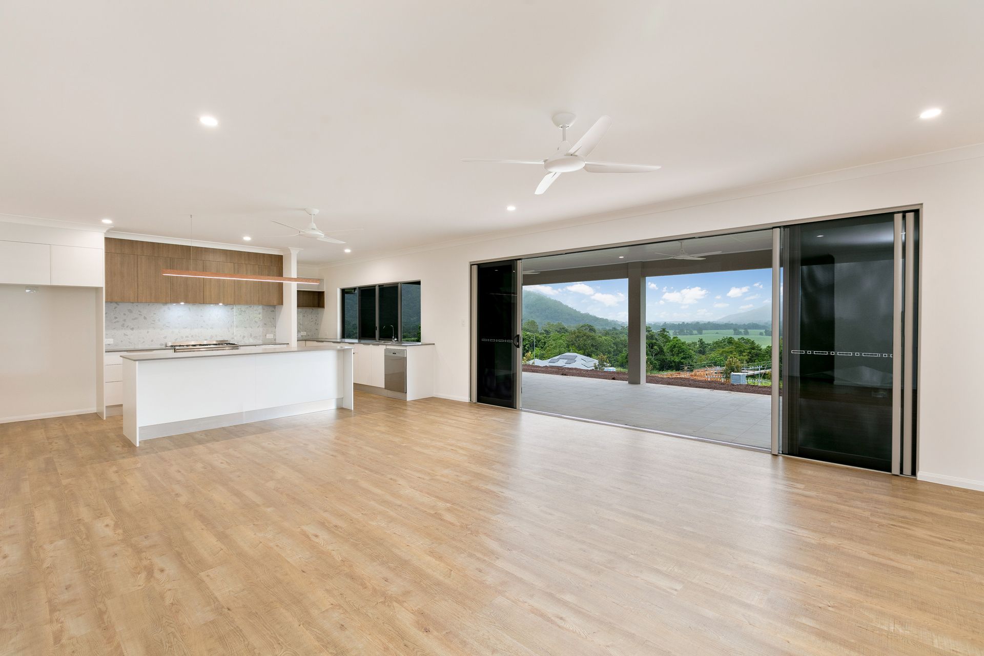 A Bright, Modern Open-plan Kitchen and Living Area With Wood Floors — Ashlee Jones Homes in Gordonvale, QLD
