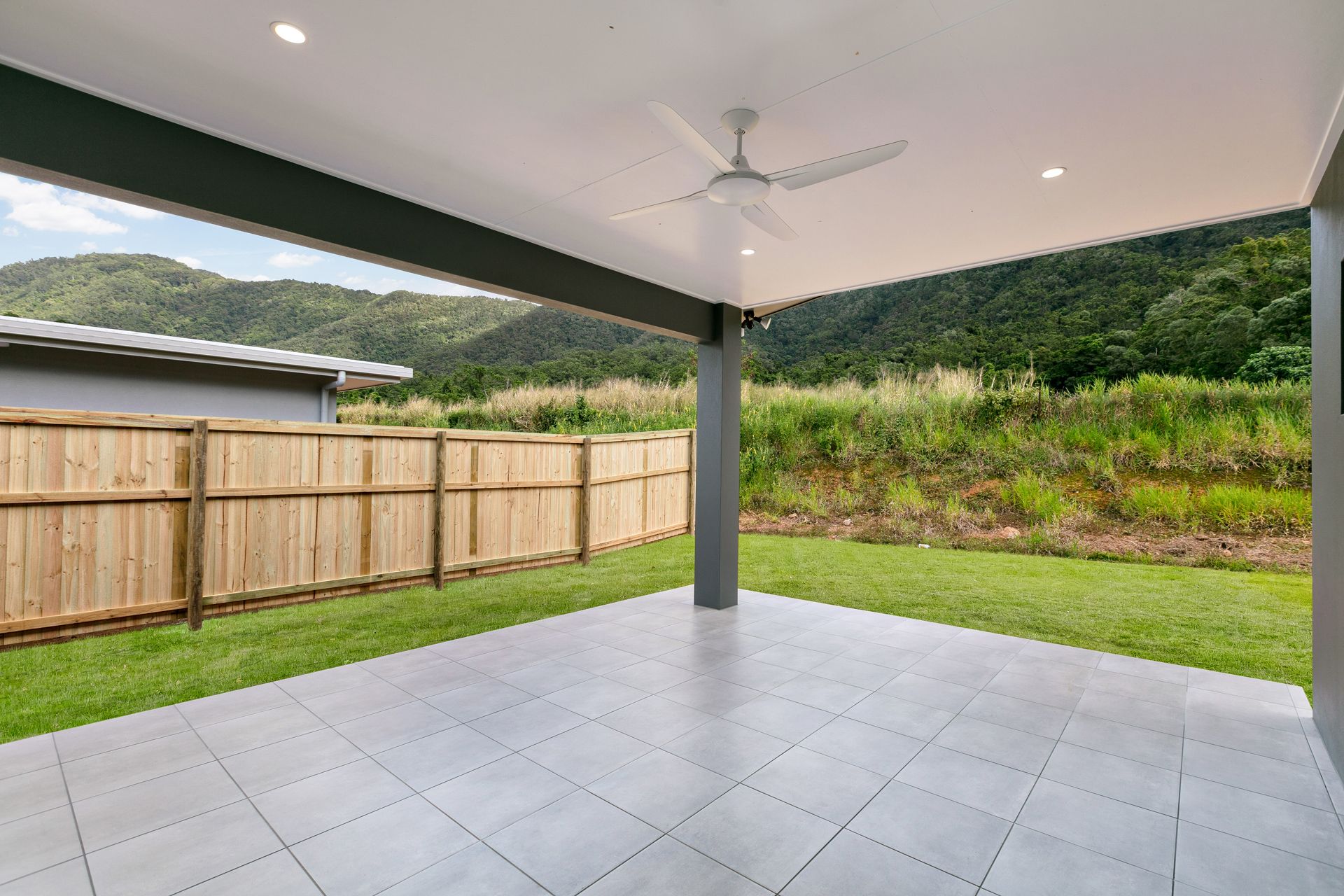 A Modern, Covered Outdoor Patio With Light Gray Tiles — Ashlee Jones Homes in Gordonvale, QLD