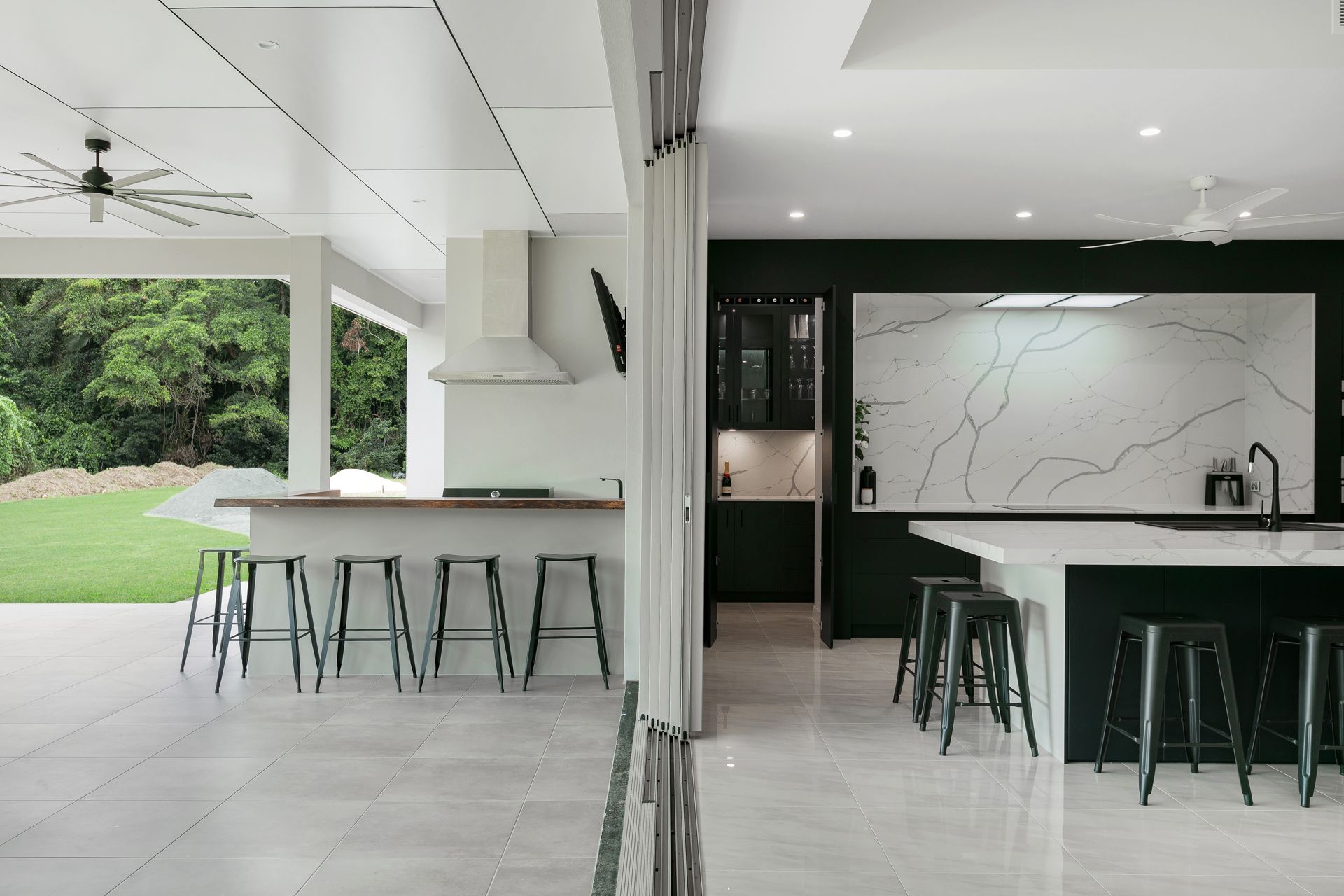 A Split View of an Indoor Kitchen With Black Cabinets — Ashlee Jones Homes in Gordonvale, QLD