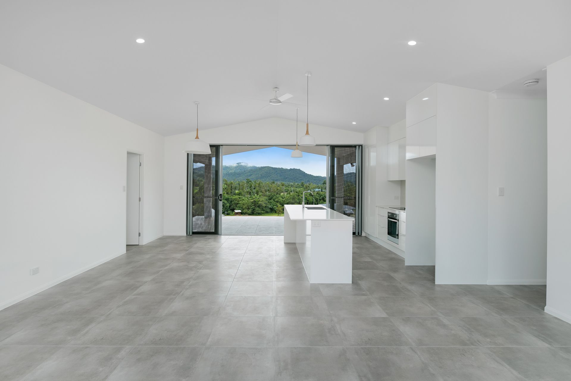 Open-plan Room With Grey Tiled Floors, a White Kitchen Island — Ashlee Jones Homes in Gordonvale, QLD