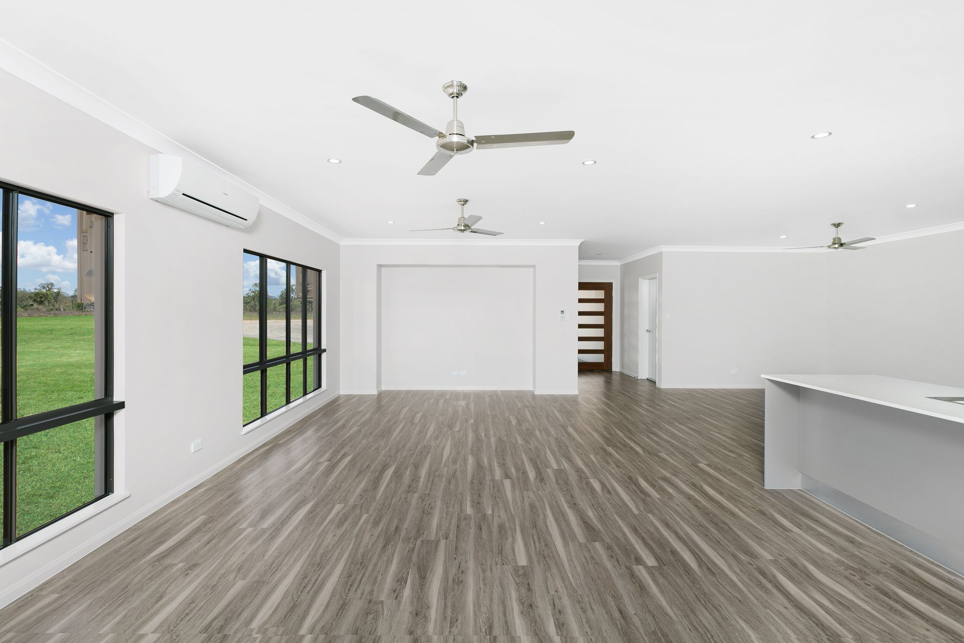 An Empty, Modern Living Area With Light Wood-look Flooring — Ashlee Jones Homes in Gordonvale, QLD