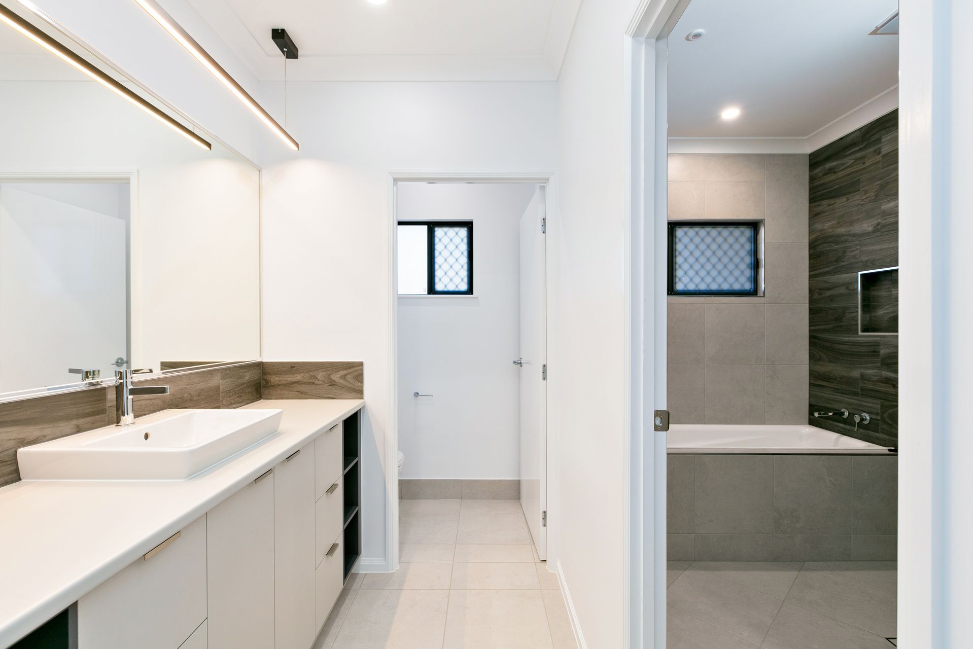 Modern Bathroom With a White Vanity, a Large Mirror — Ashlee Jones Homes in Gordonvale, QLD