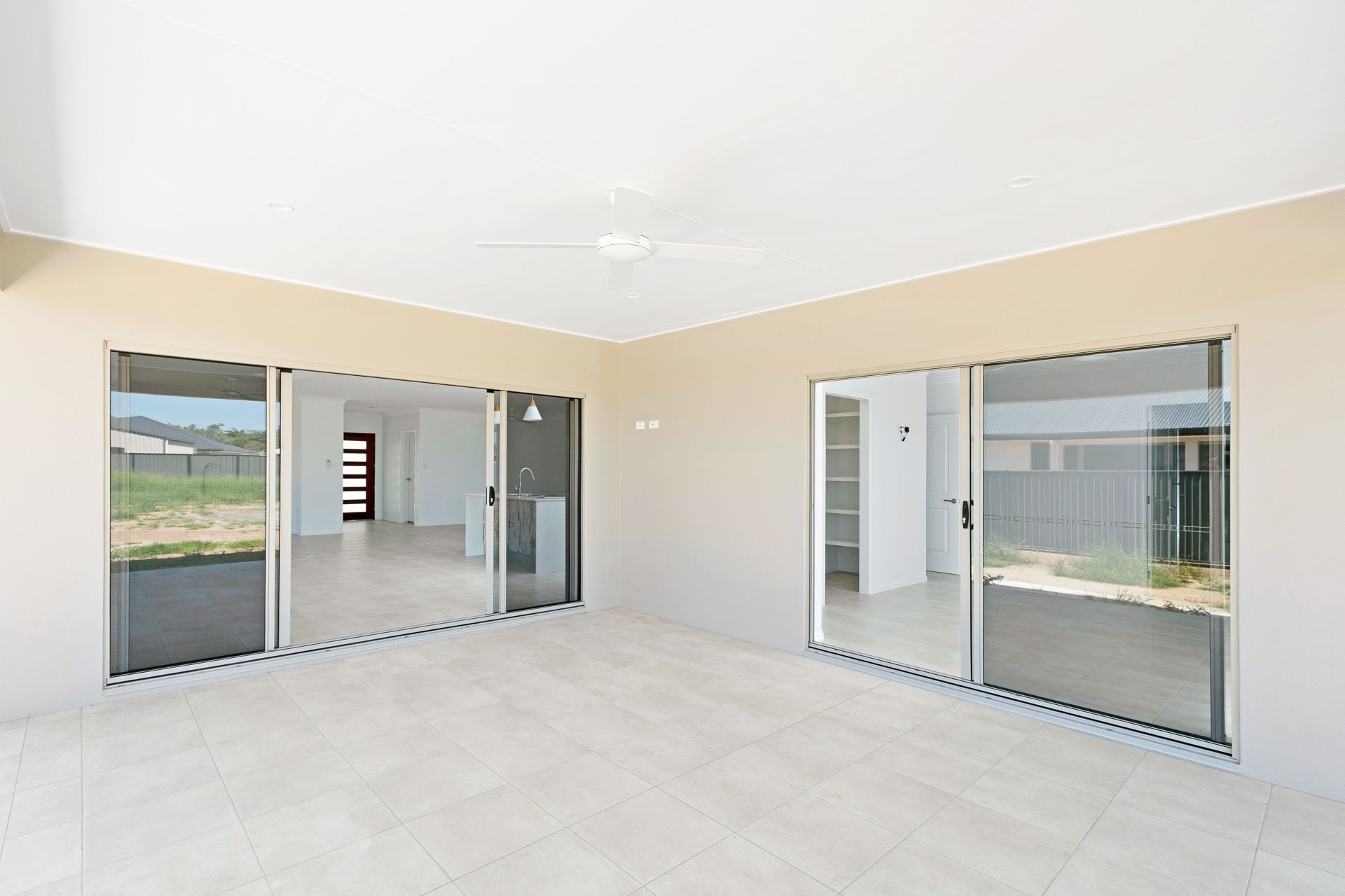 A Covered Outdoor Patio With Light Tiled Flooring, White Walls — Ashlee Jones Homes in Gordonvale, QLD