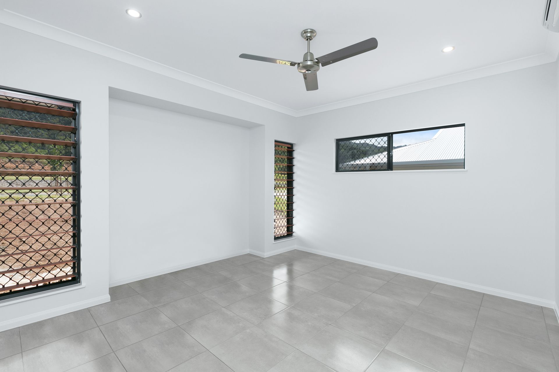 An Empty, Minimalist Room With Light Gray Tile Floors — Ashlee Jones Homes in Gordonvale, QLD