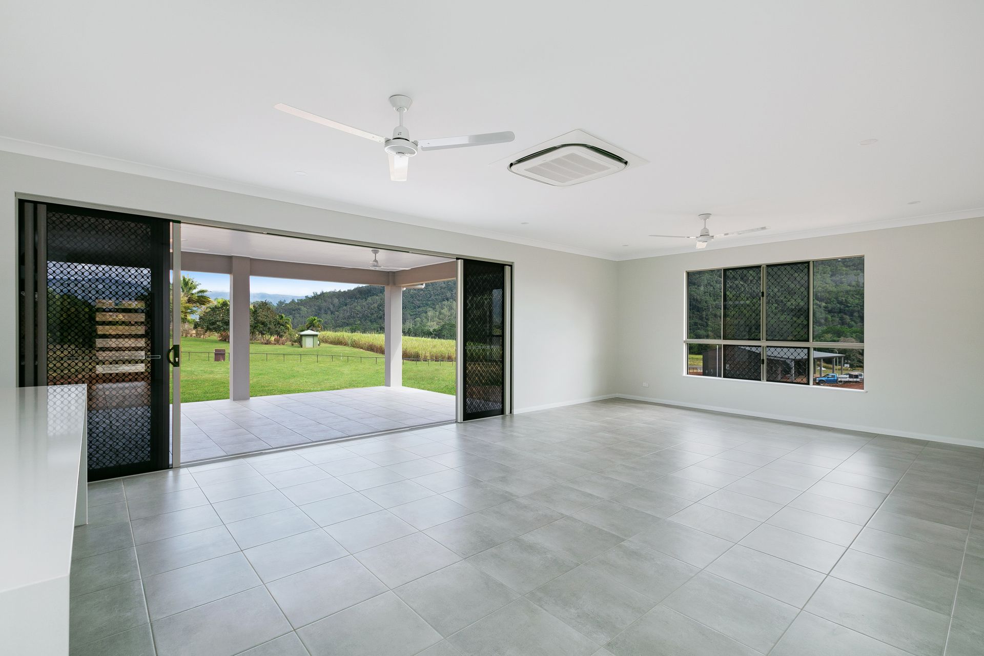 A Spacious Room With Light Gray Tile Flooring — Ashlee Jones Homes in Gordonvale, QLD