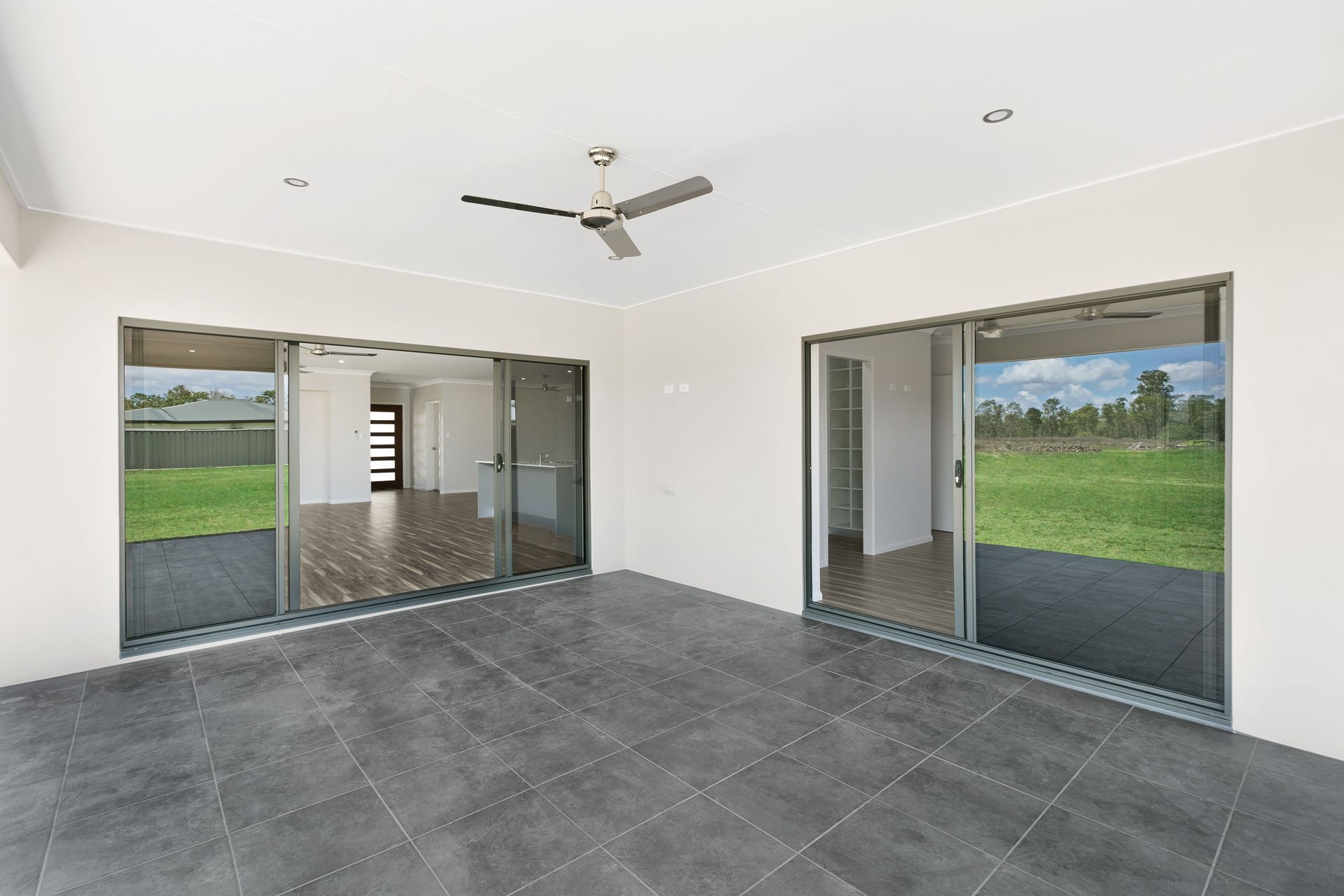 A Covered Outdoor Patio With Dark Gray Tiled Flooring — Ashlee Jones Homes in Gordonvale, QLD