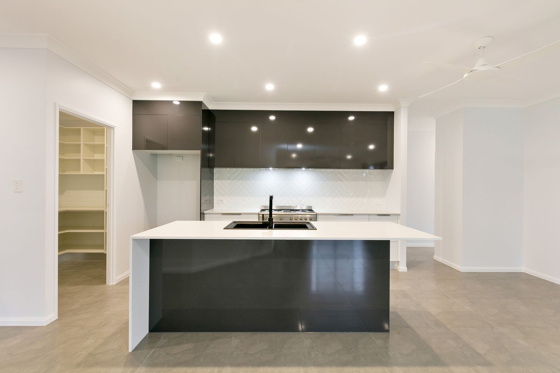 A Modern Kitchen Featuring a Dark Island With a White Countertop — Ashlee Jones Homes in Gordonvale, QLD