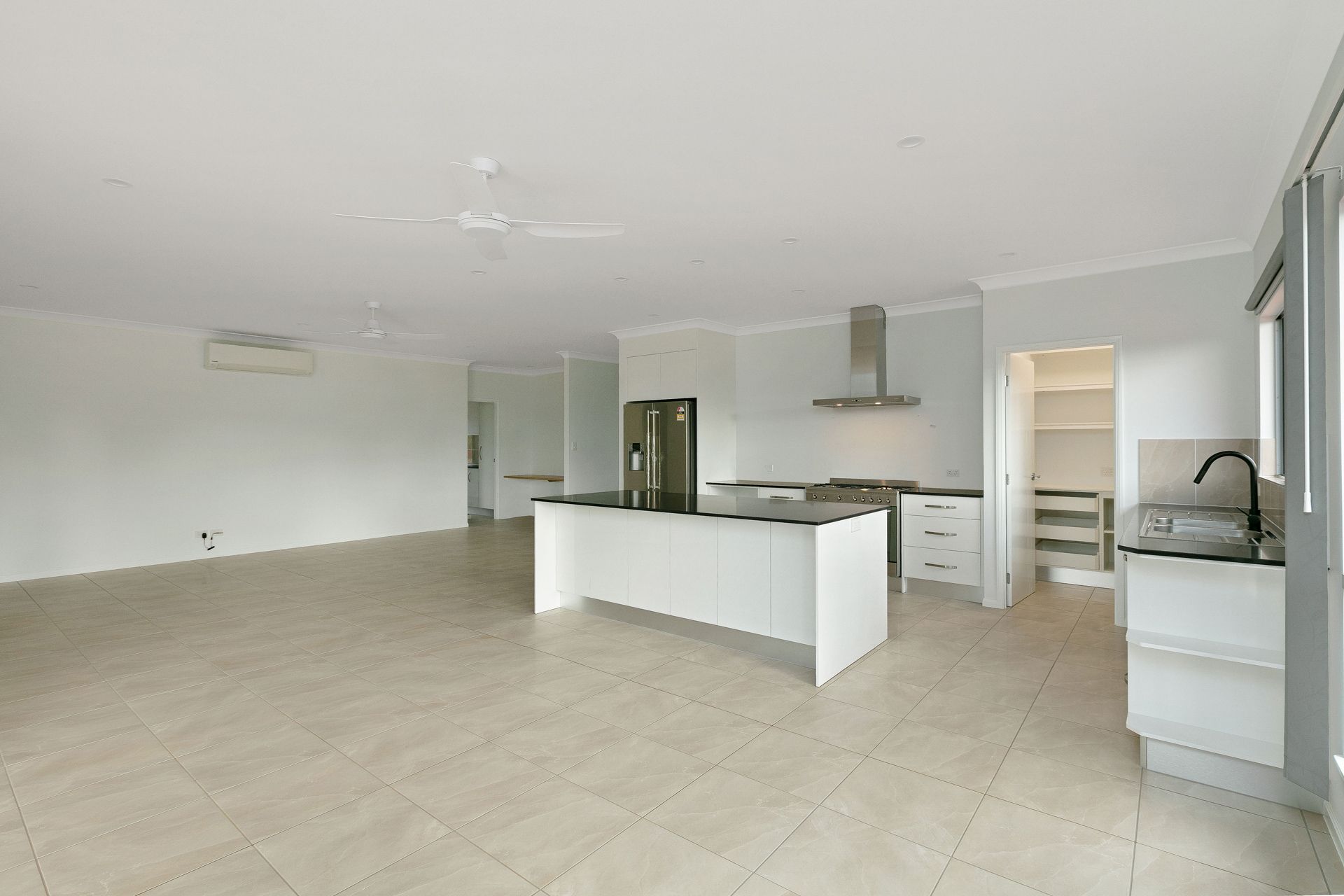 Modern, Bright, Open-plan Kitchen and Living Area With White Cabinetry — Ashlee Jones Homes in Gordonvale, QLD