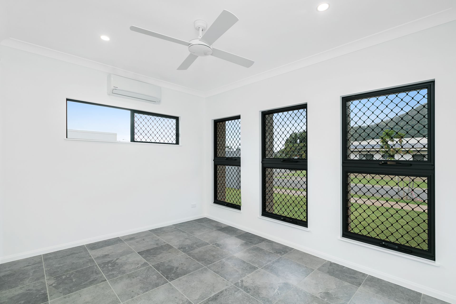 A Minimalist Room With White Walls, Gray Tile Flooring, a Ceiling Fan — Ashlee Jones Homes in Gordonvale, QLD