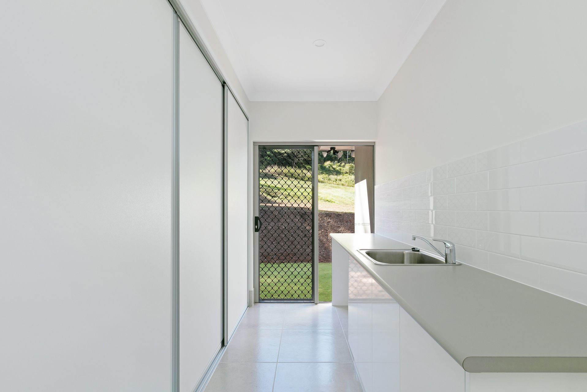 A White Galley-style Kitchen With a Long Counter — Ashlee Jones Homes in Gordonvale, QLD
