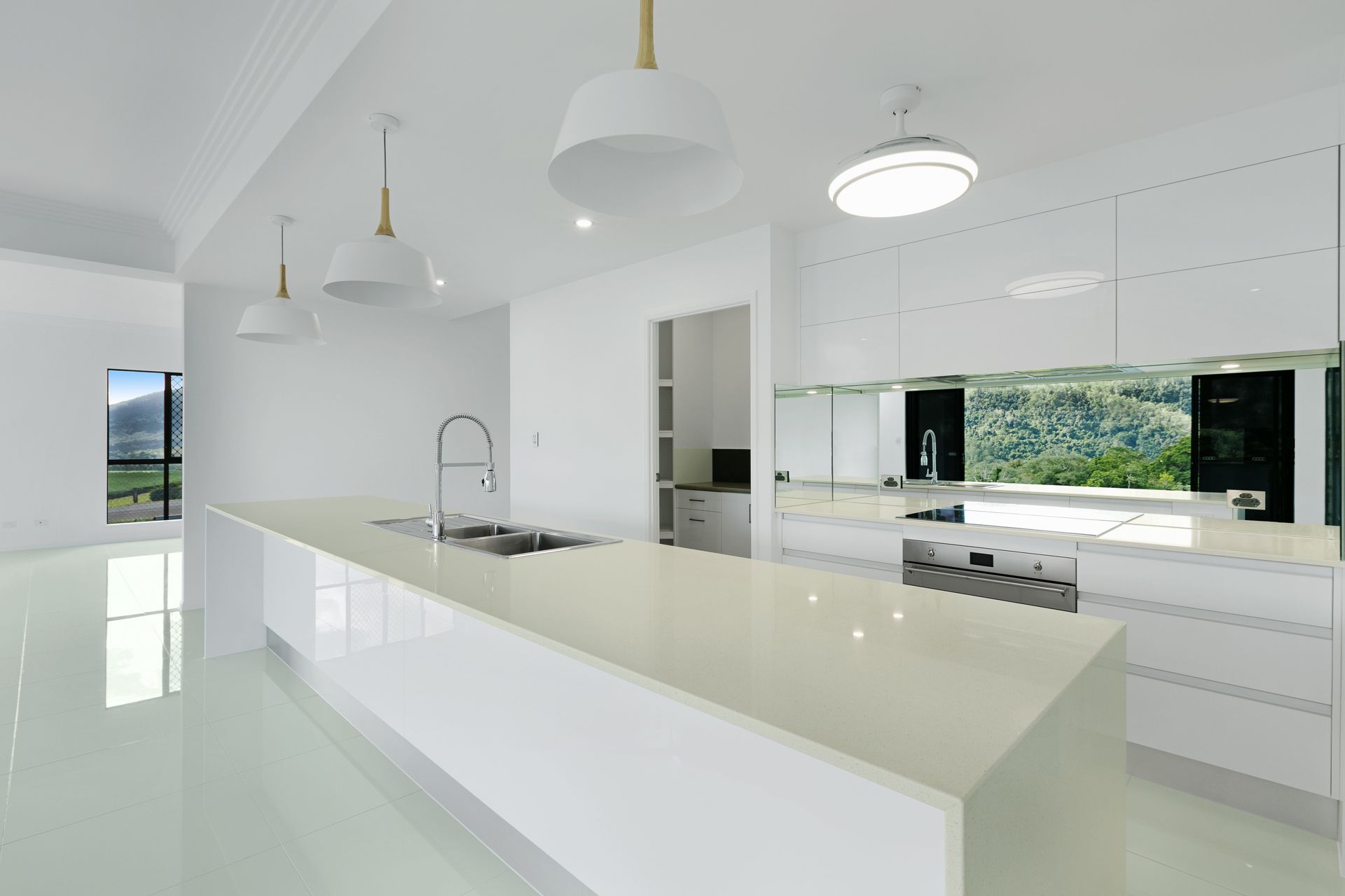 Modern White Kitchen With a Long Island, Sleek Cabinets — Ashlee Jones Homes in Gordonvale, QLD