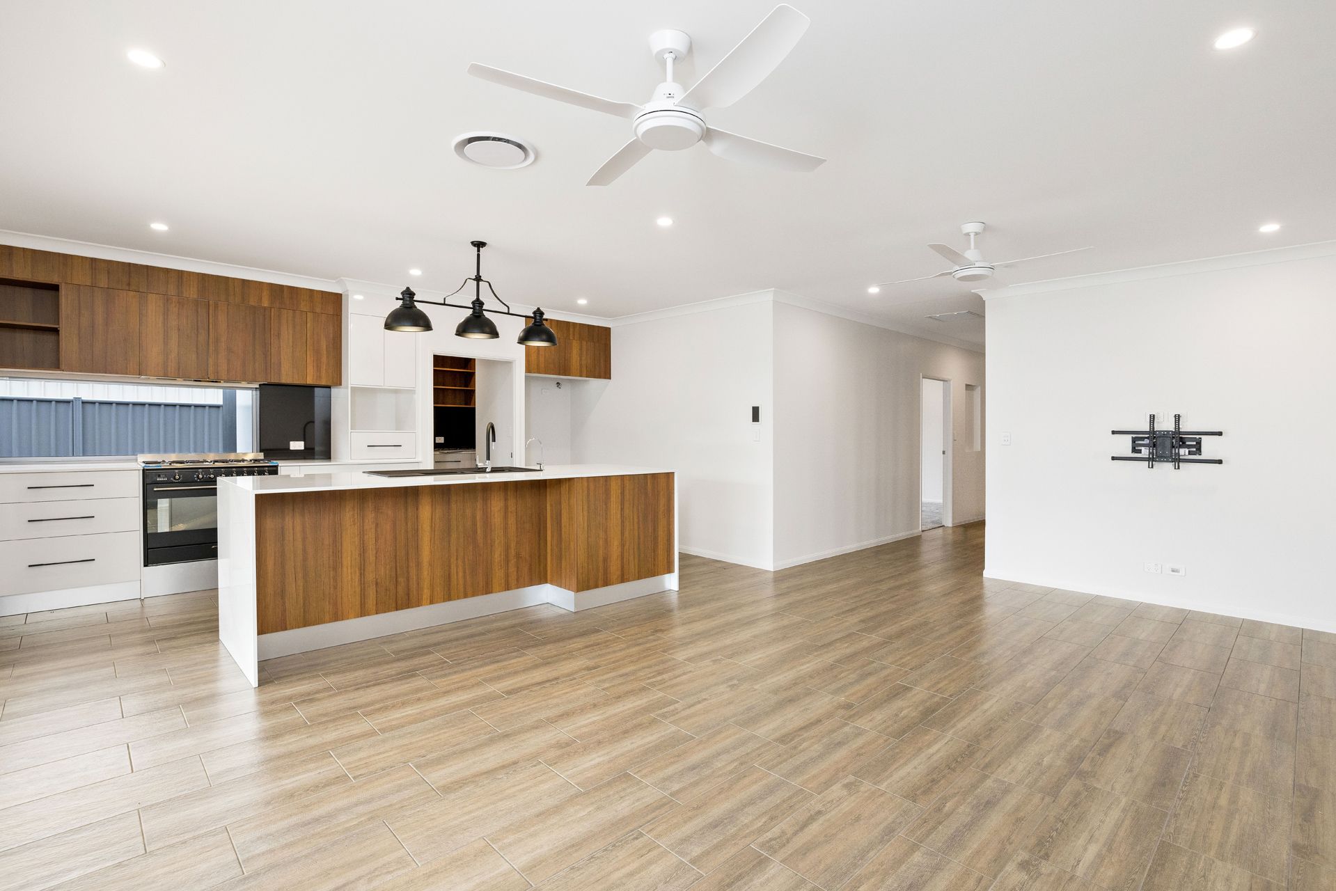 A Bright Open-plan Kitchen and Living Area Featuring Wood Cabinetry — Ashlee Jones Homes in Gordonvale, QLD