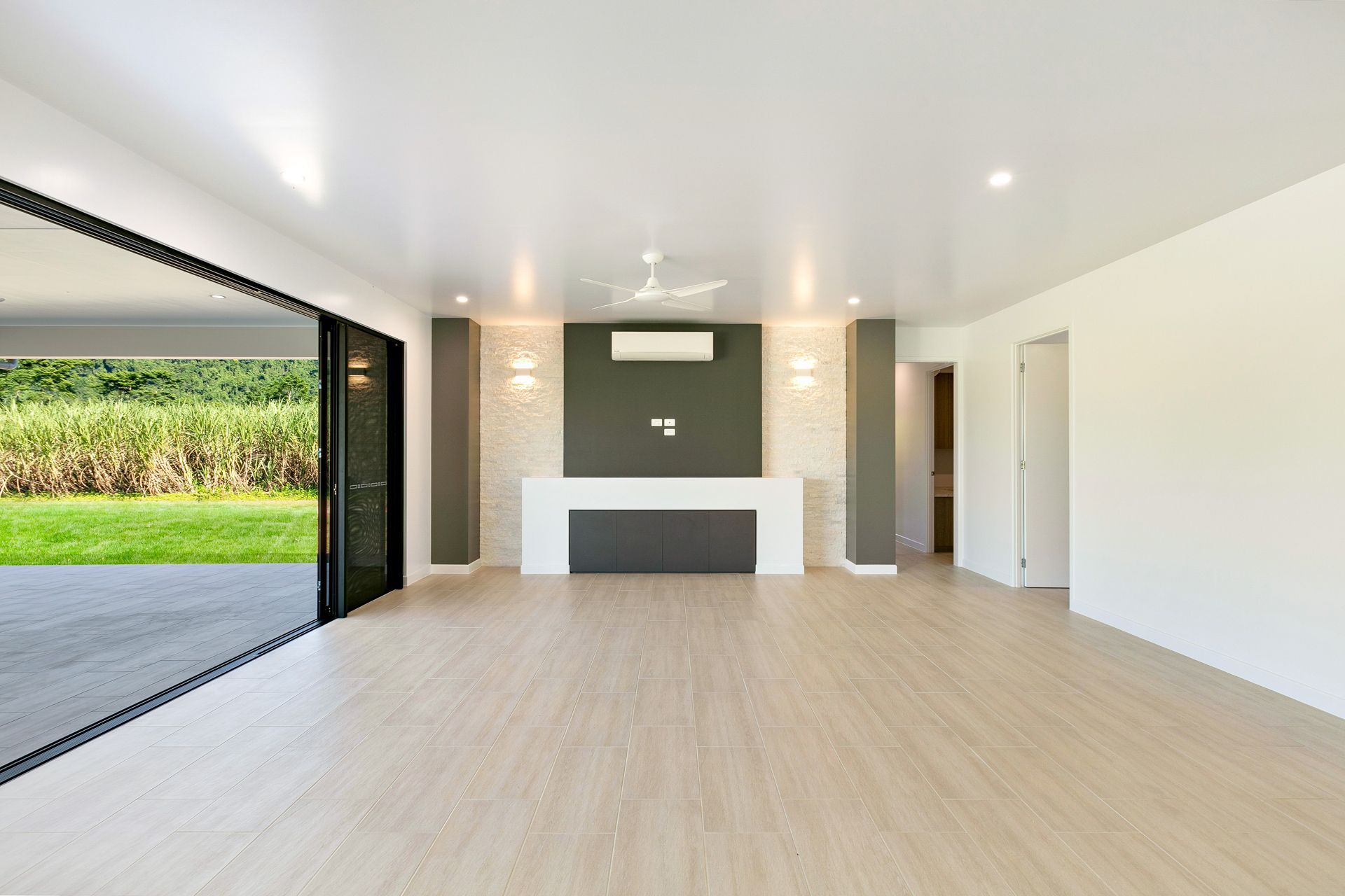 A Modern, Empty Living Room With Light Wood Floors — Ashlee Jones Homes in Gordonvale, QLD