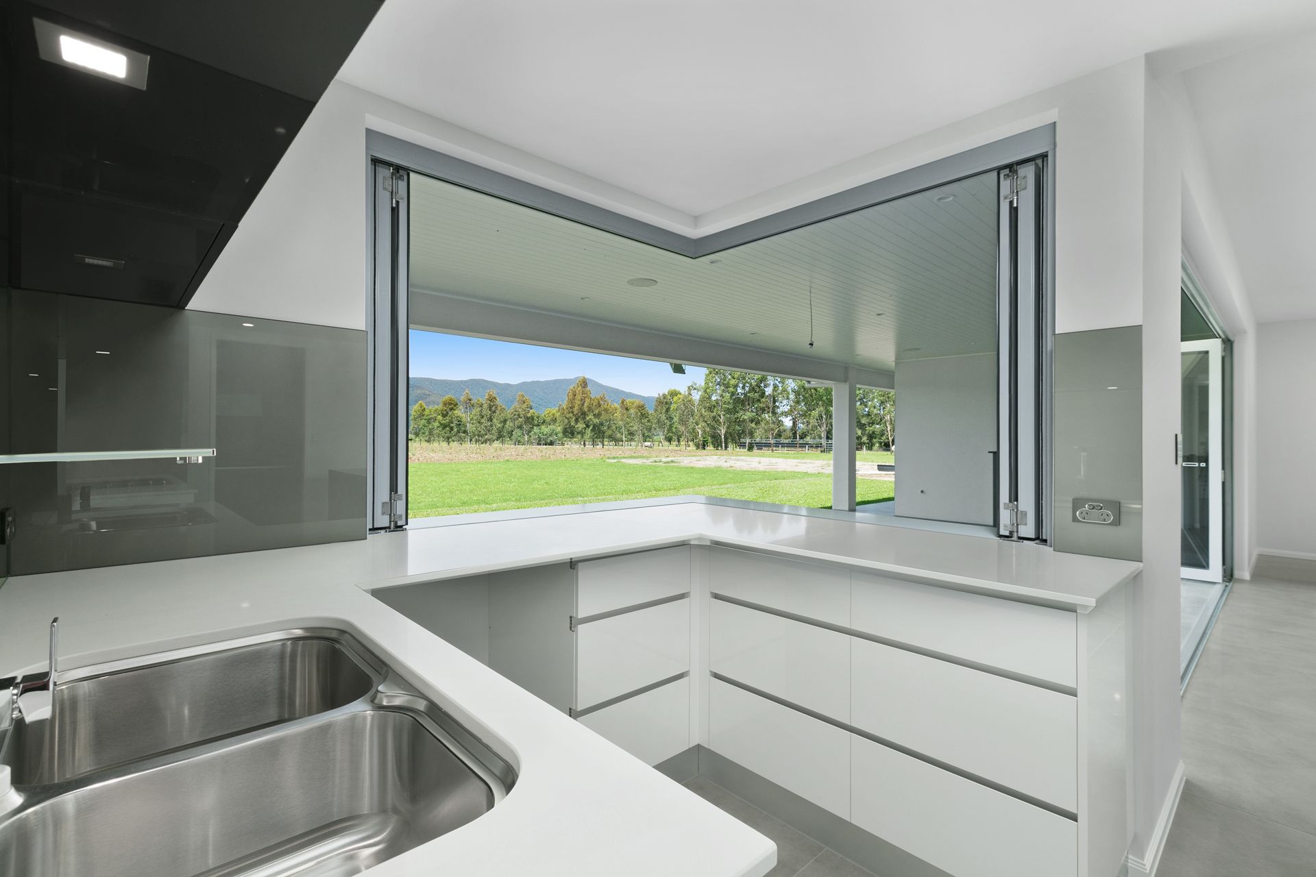 A Modern White Kitchen With a Stainless Steel Sink — Ashlee Jones Homes in Gordonvale, QLD