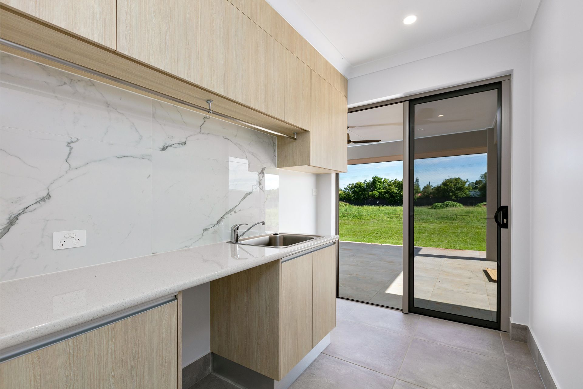 A Modern Kitchen Laundry Room With Light Wood Cabinets — Ashlee Jones Homes in Gordonvale, QLD
