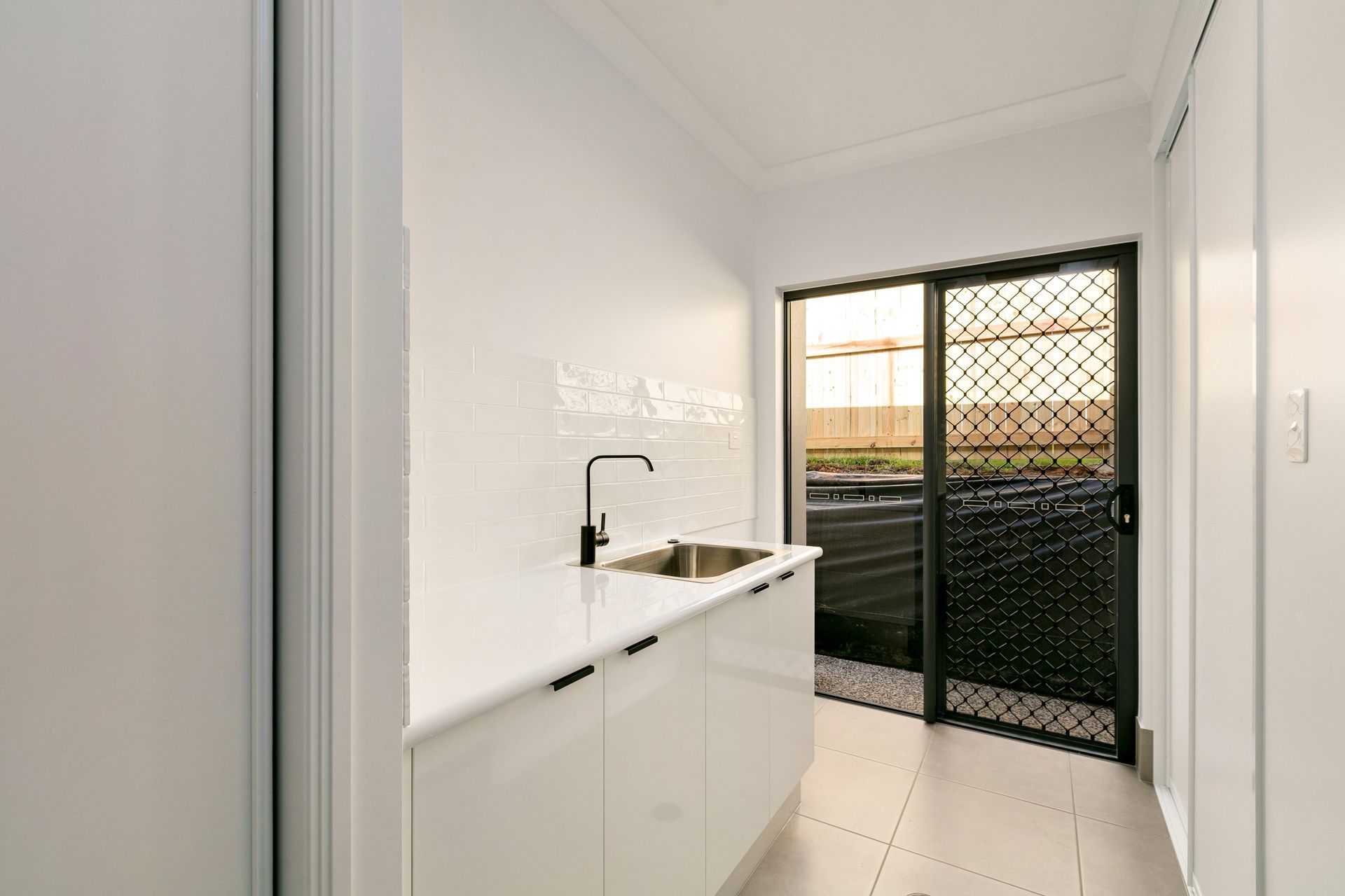 A White, Modern Laundry Room With a Sink and Countertop — Ashlee Jones Homes in Gordonvale, QLD