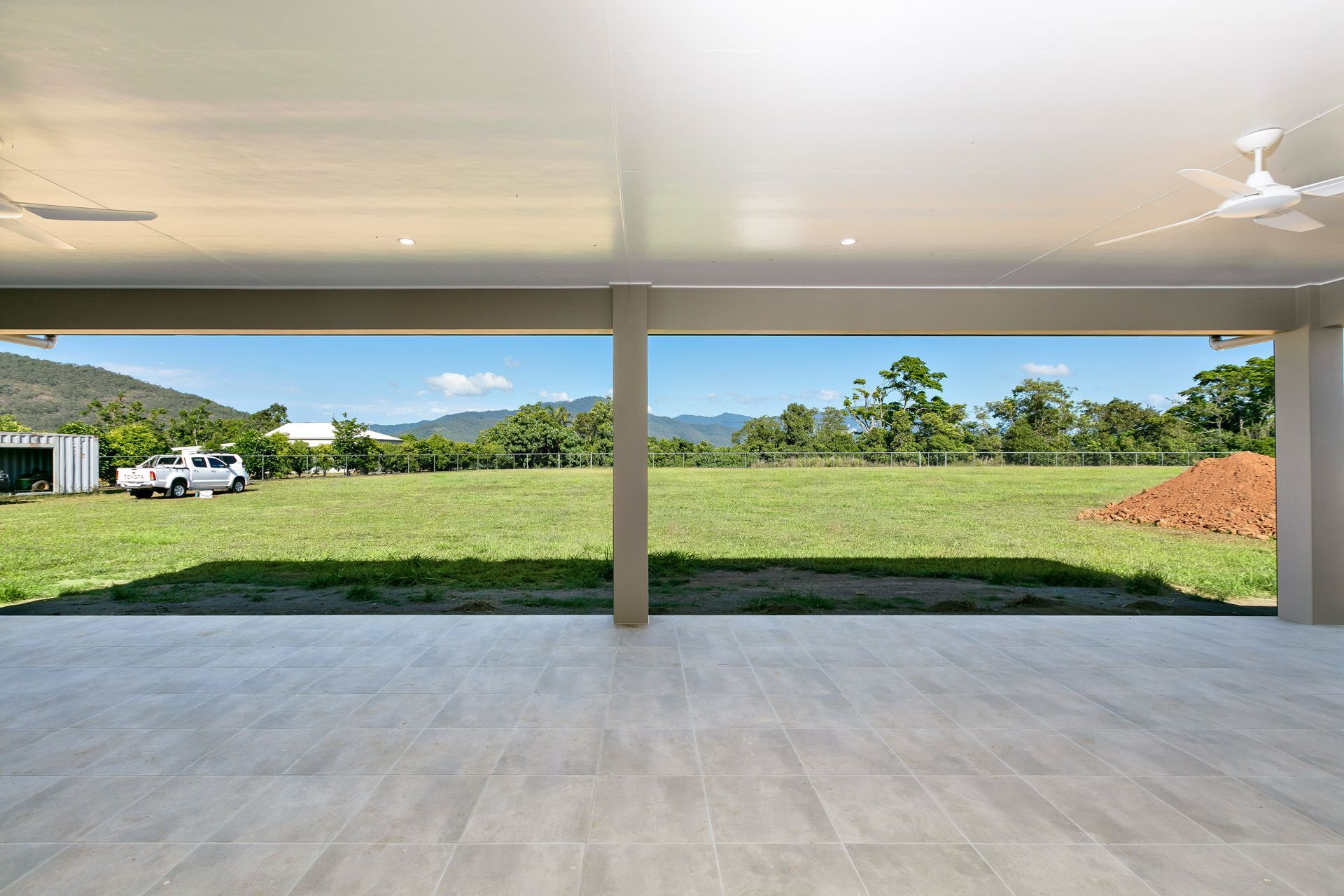 A View From a Tiled Covered Patio Looking Out Over a Grassy Field — Ashlee Jones Homes in Gordonvale, QLD