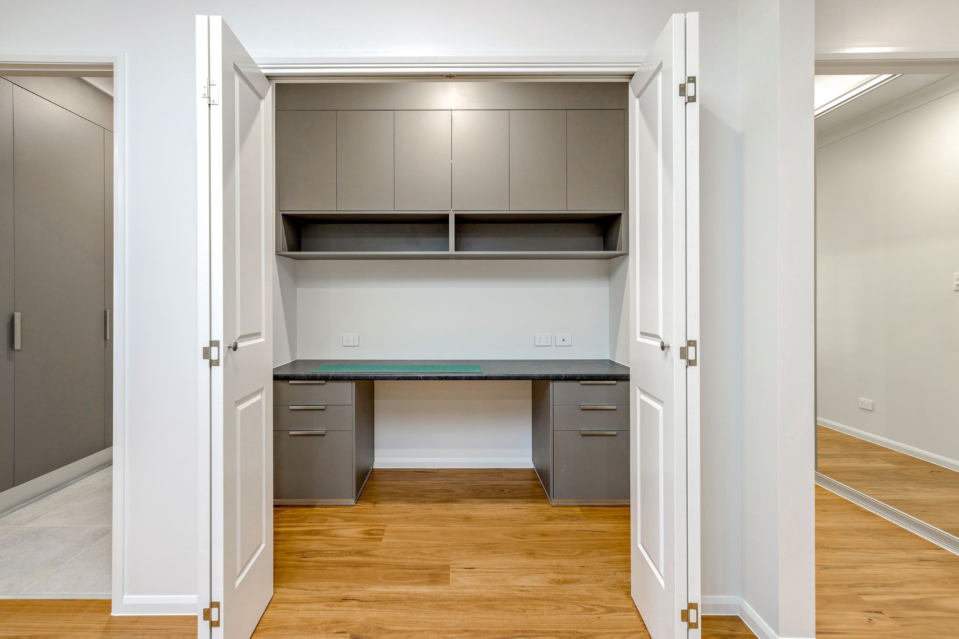 A Built-in Home Office Desk Inside an Open Closet With Grey Cabinets — Ashlee Jones Homes in Gordonvale, QLD