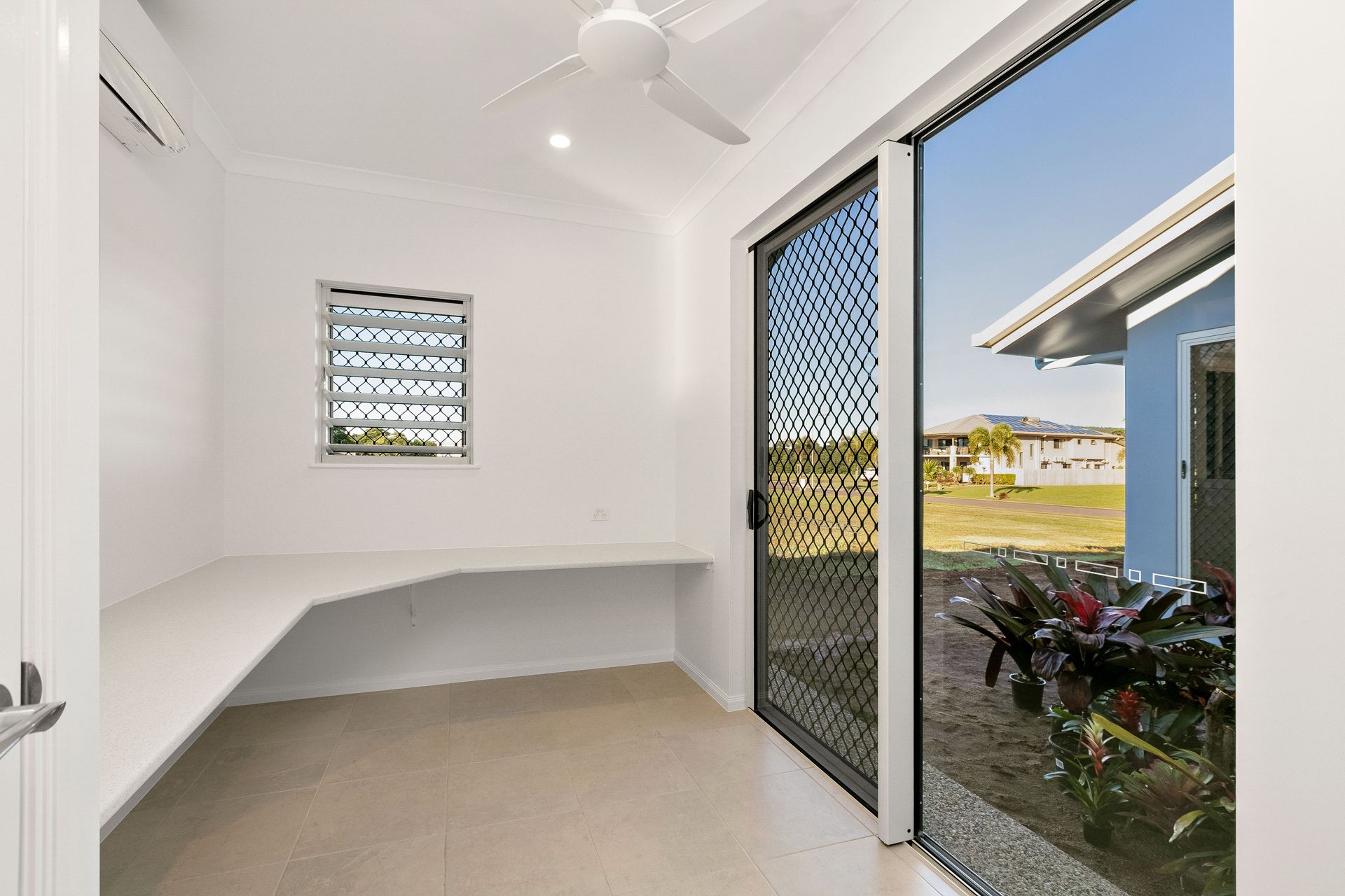 A Small Room With a White Desk, Louver Window — Ashlee Jones Homes in Gordonvale, QLD