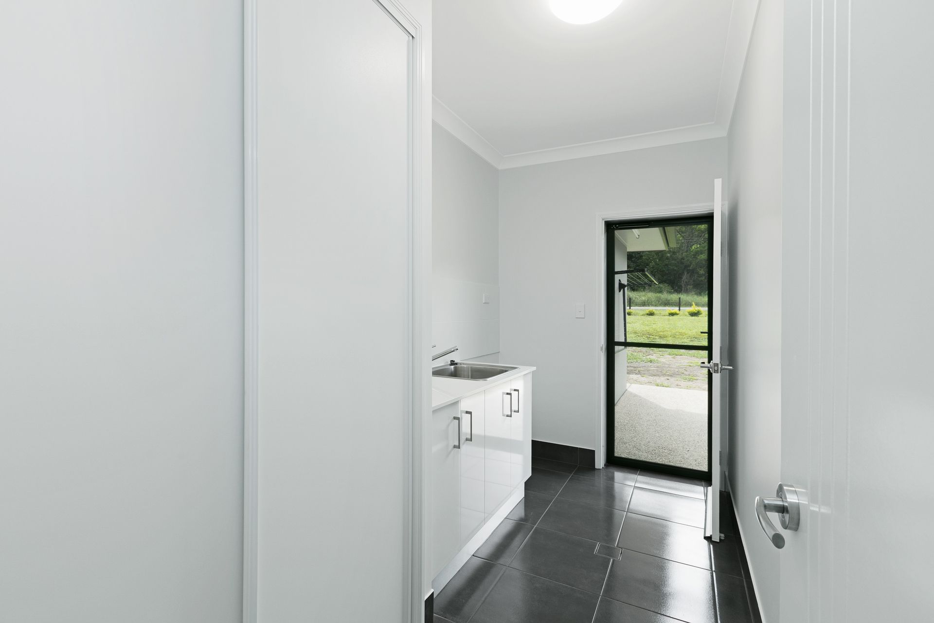 A Brightly Lit Laundry or Utility Room With White Cabinets — Ashlee Jones Homes in Gordonvale, QLD