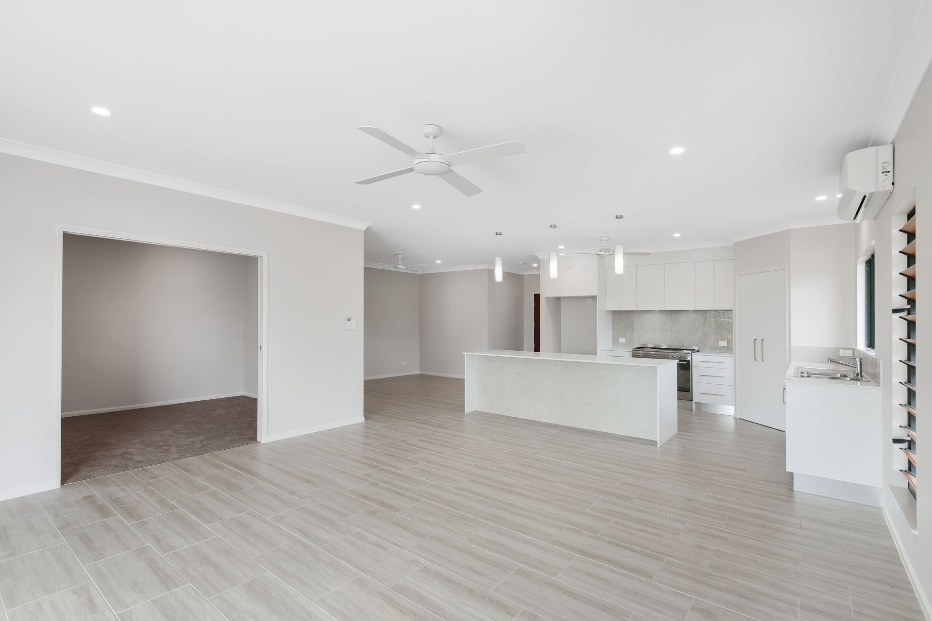 An Open-plan Living and Kitchen Area With Light-colored Tile Floors — Ashlee Jones Homes in Gordonvale, QLD