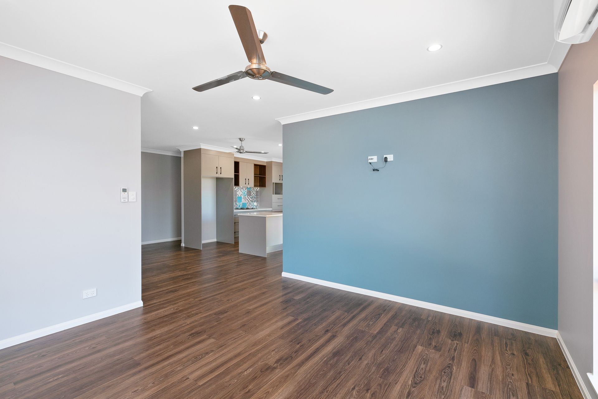 A Bright, Empty Living Room With Wood Flooring, a Ceiling Fan — Ashlee Jones Homes in Gordonvale, QLD