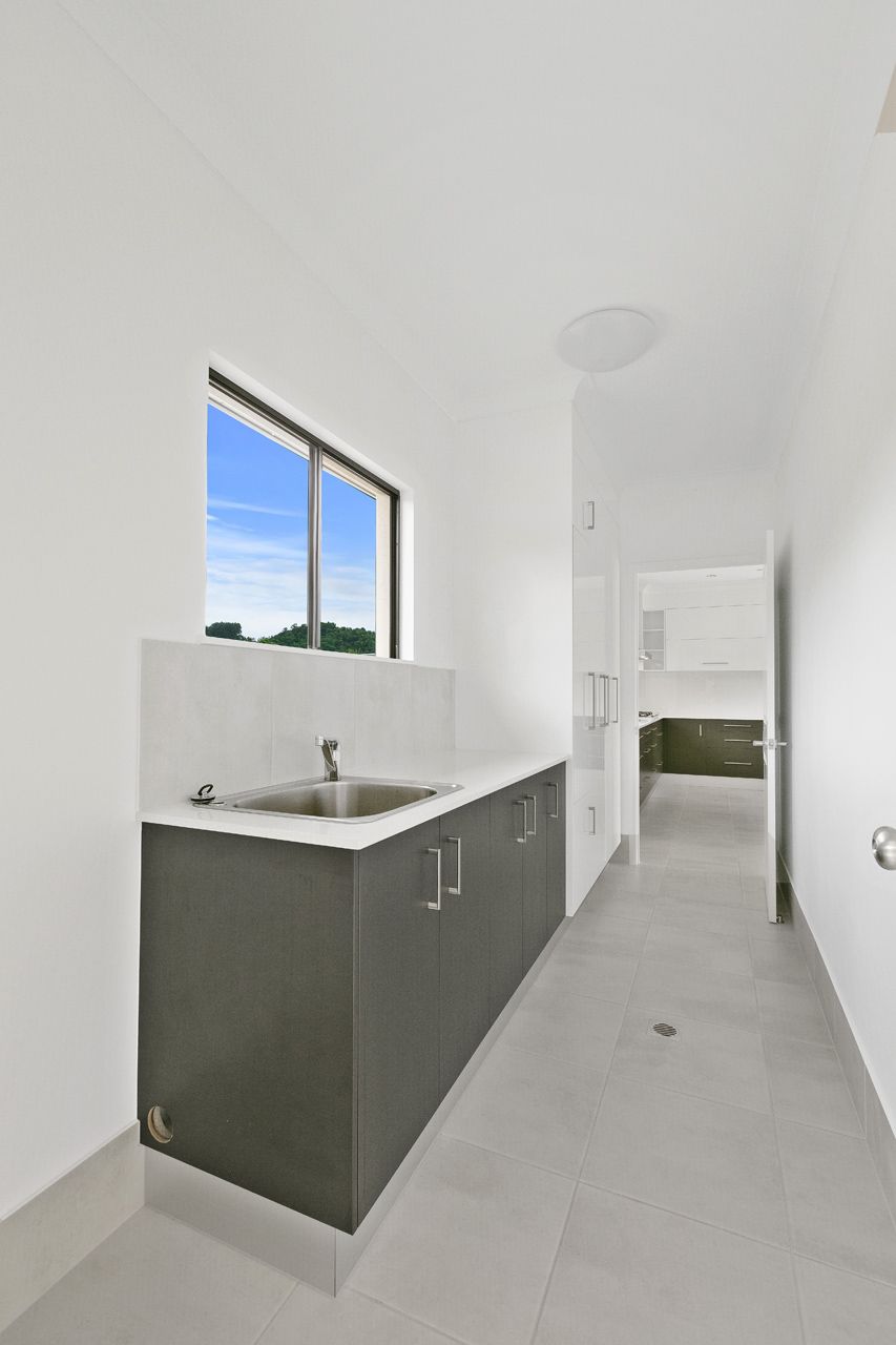 A Bright, Modern Laundry Room Featuring a Dark Grey Cabinet With a Sink — Ashlee Jones Homes in Gordonvale, QLD