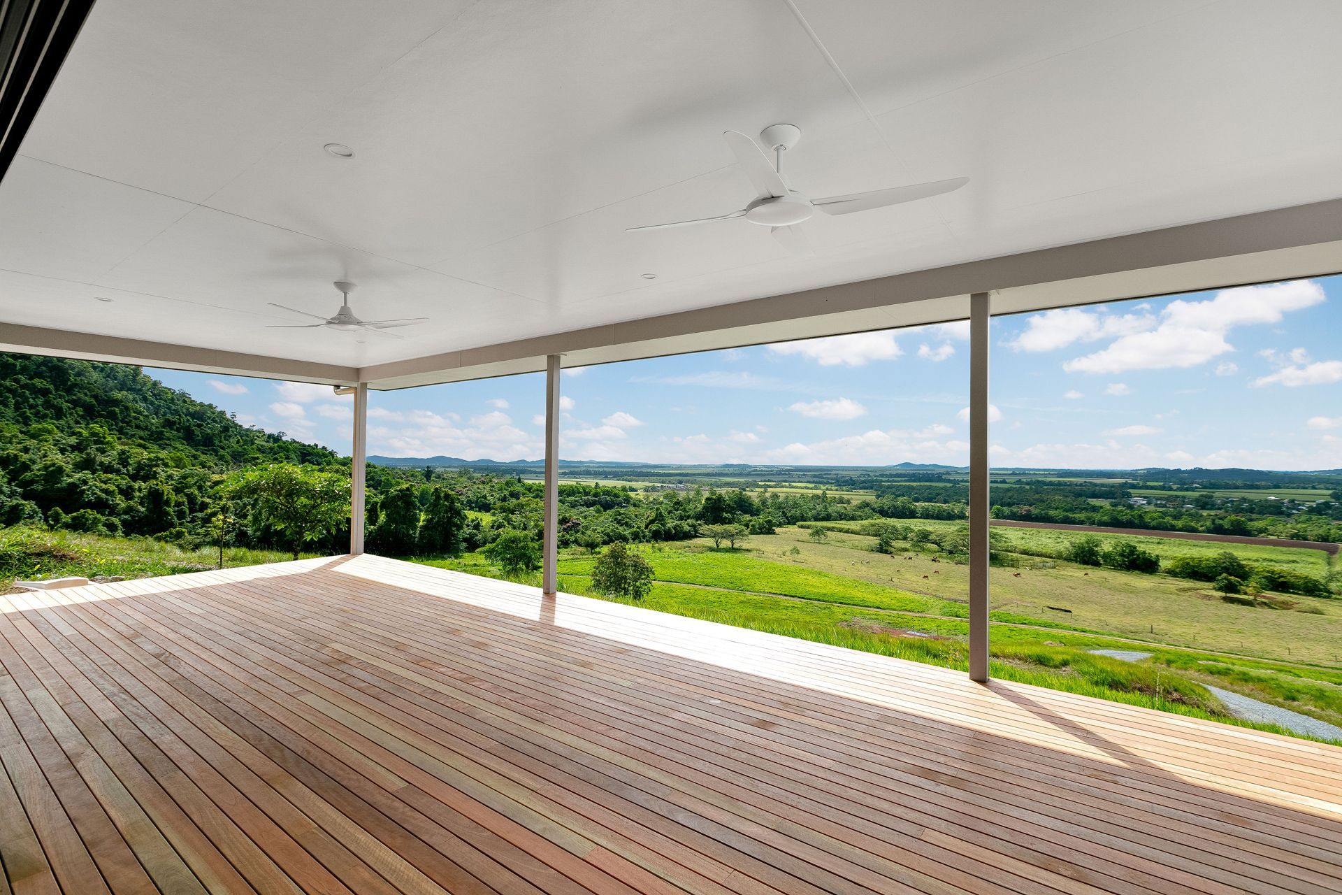 A Wide, Covered Wooden Deck Overlooks a Lush — Ashlee Jones Homes in Gordonvale, QLD