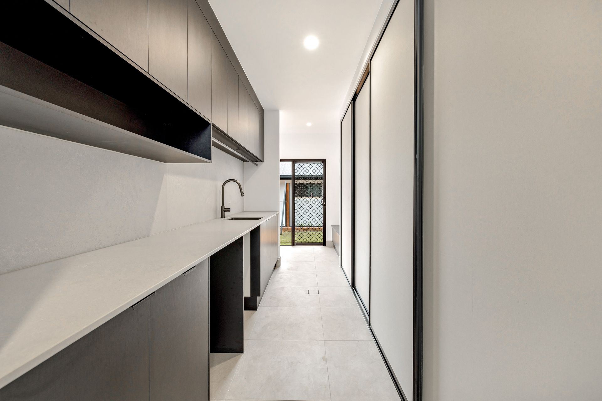 A Narrow, Modern Laundry Room With Dark Cabinetry — Ashlee Jones Homes in Gordonvale, QLD