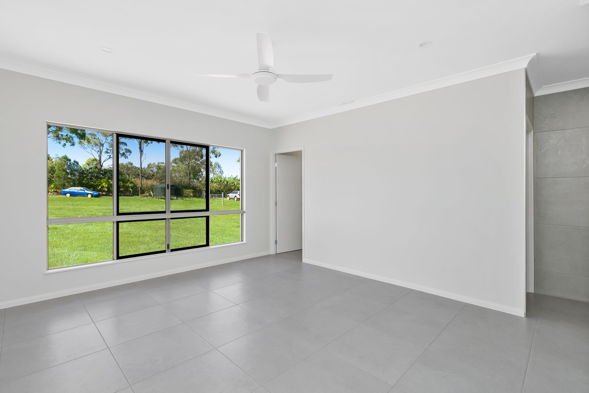A Bright, Empty Room With Light Grey Tiled Floors — Ashlee Jones Homes in Gordonvale, QLD