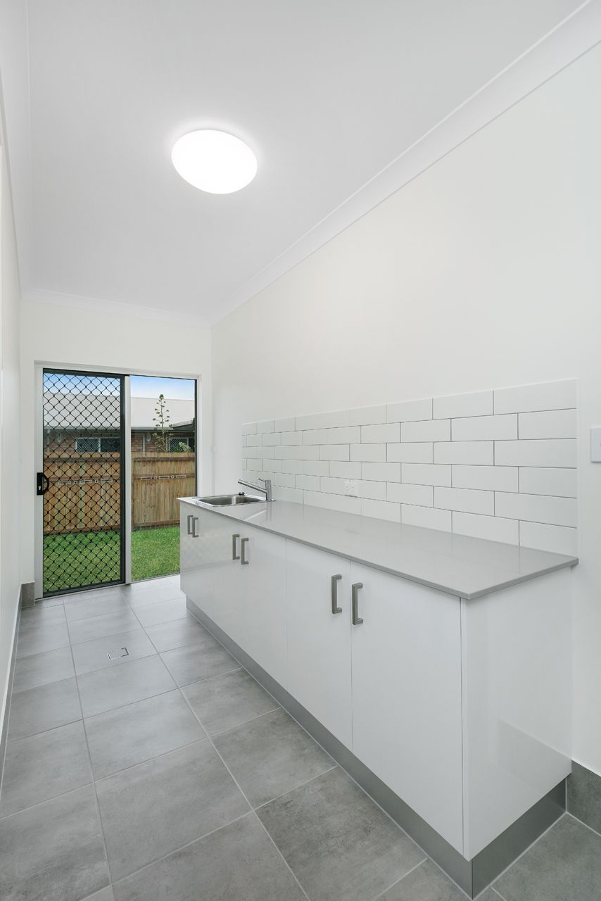 A Laundry Area With White Cabinets, a Light Gray Countertop — Ashlee Jones Homes in Gordonvale, QLD