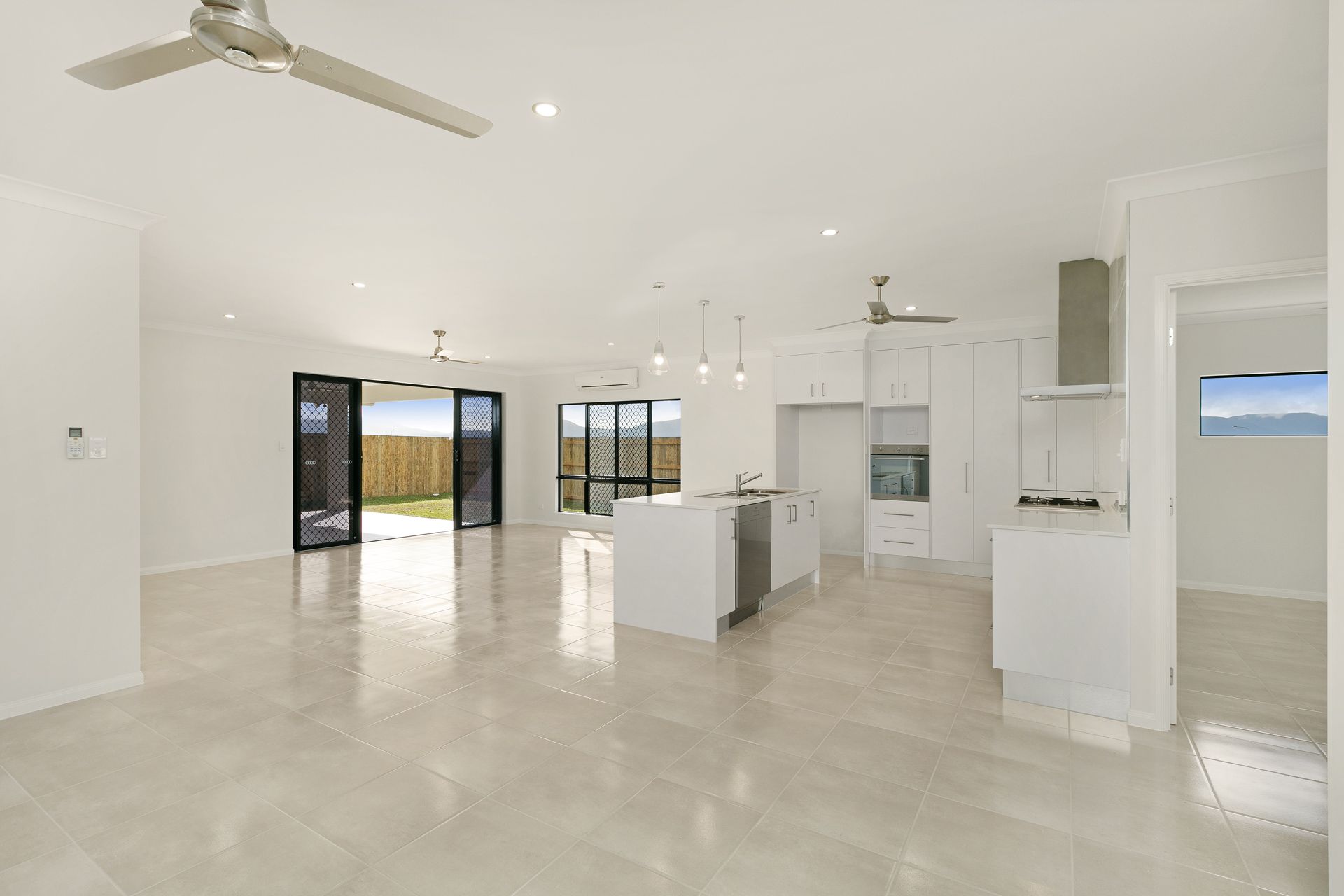 A Bright, Modern Open-plan Kitchen and Living Area With White Walls — Ashlee Jones Homes in Gordonvale, QLD